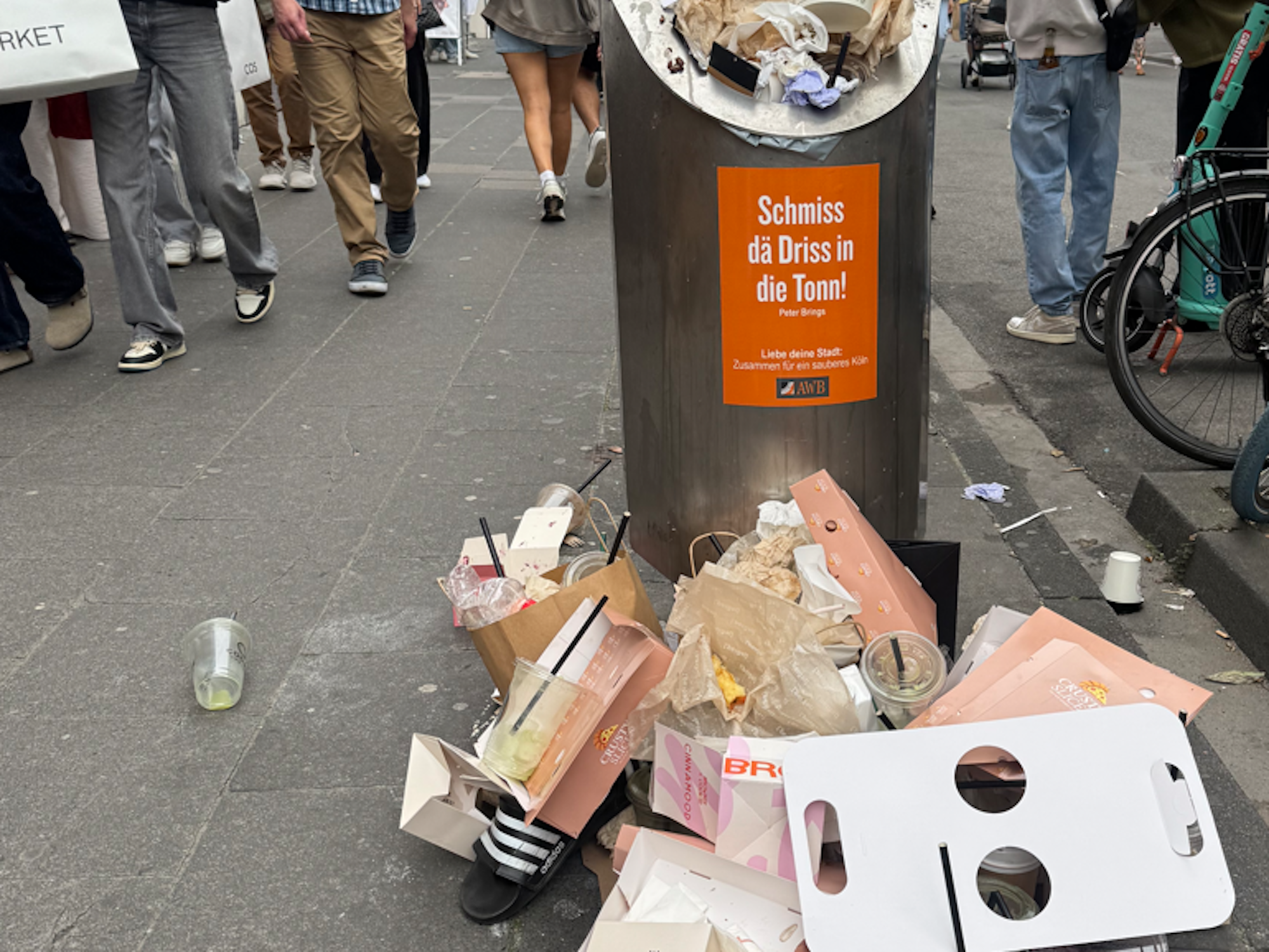 Vor einem Mülleimer stapelt sich Müll.