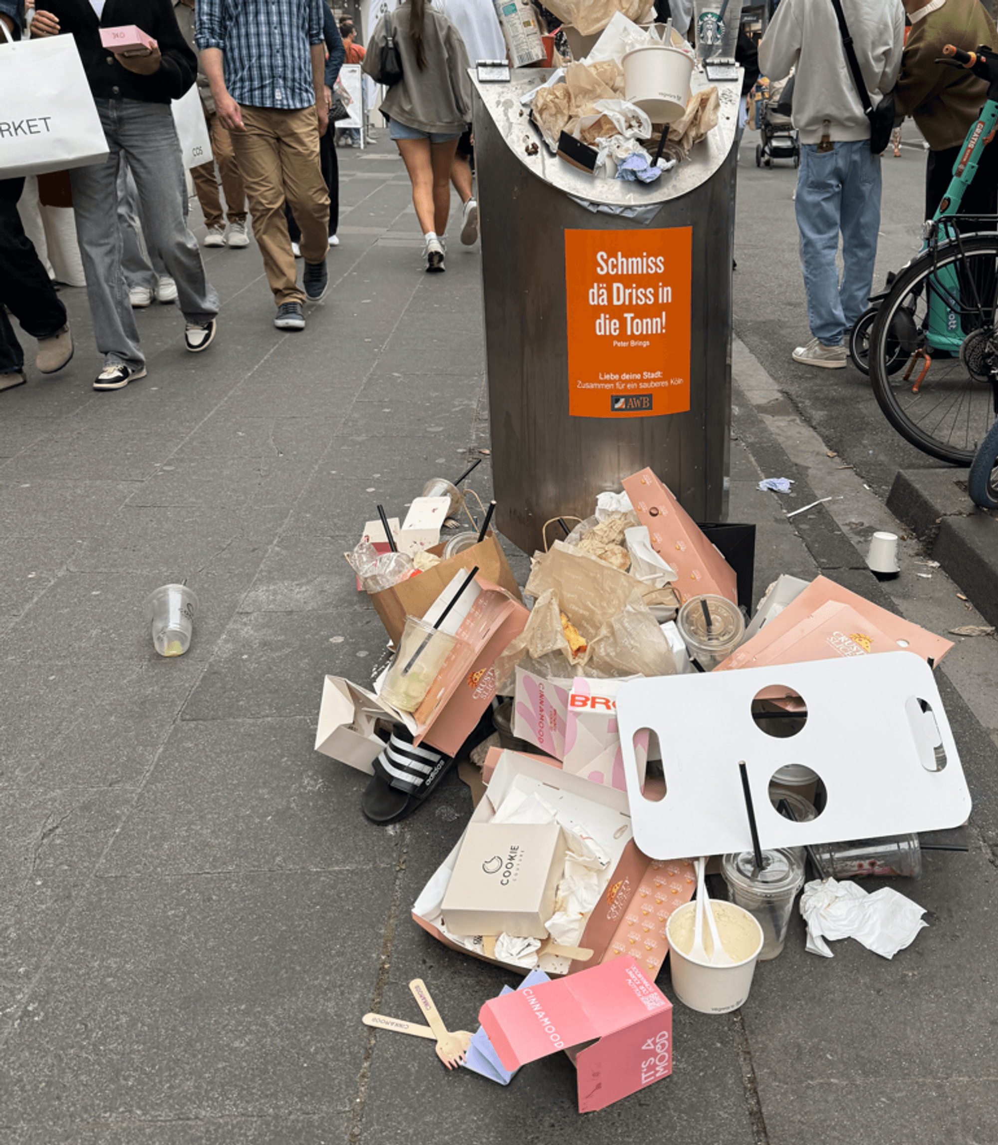 Ein übervoller Mülleimer auf der Kölner Ehrenstraße, Müll liegt auch auf dem Boden