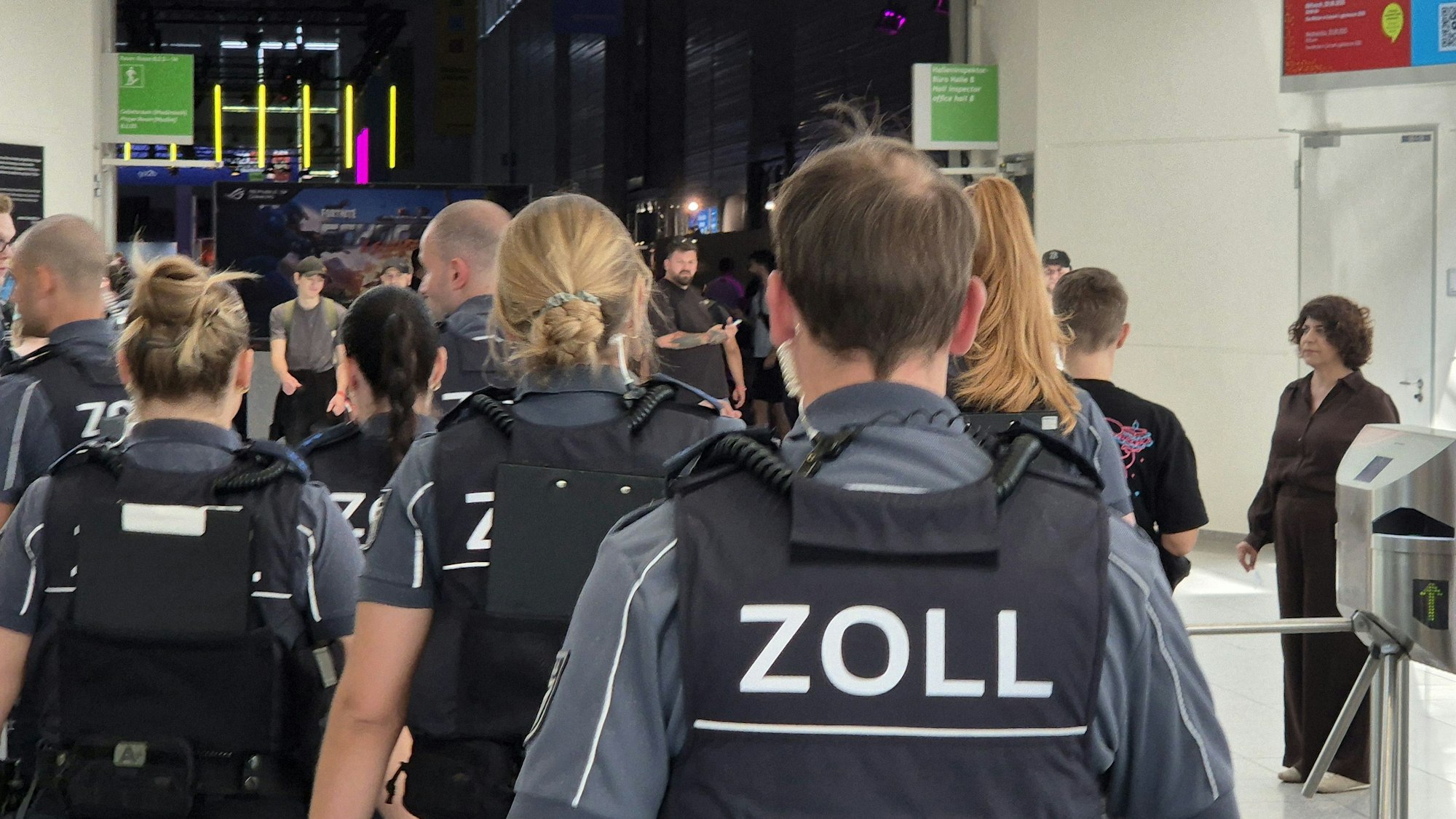 Einsatzkräfte des Zoll laufen durch eine Messehalle während der Messe Gamescom.