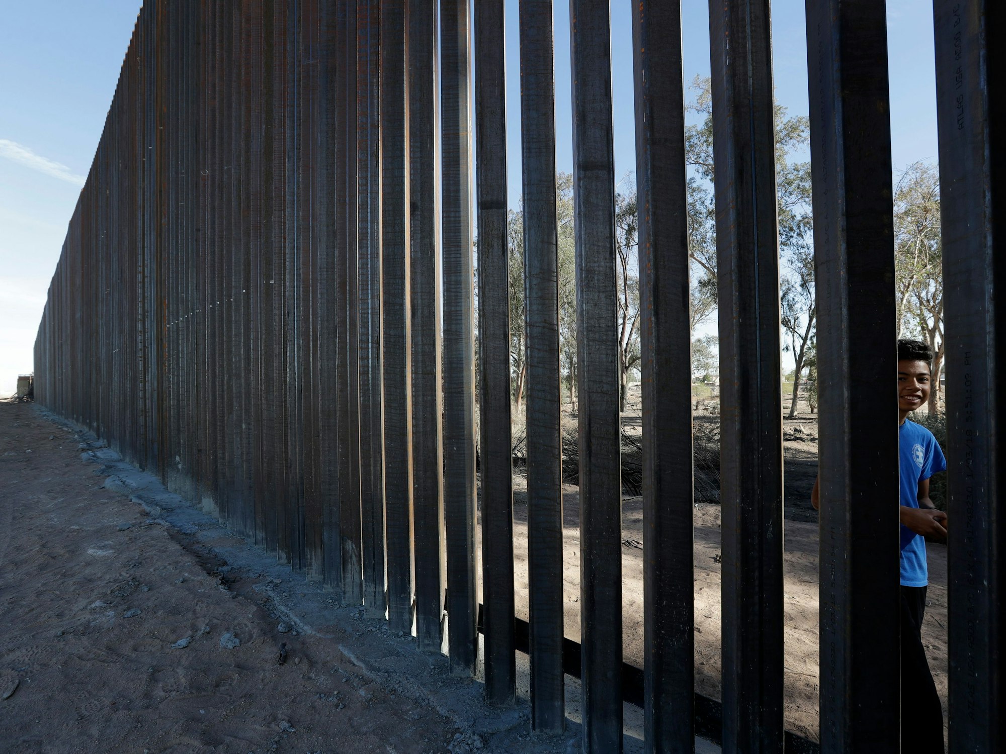 Ein Junge blickt durch die Stäbe eines neuen Grenzzaunes entlang der US-amerikanischen Grenze zwischen Calexico (USA, links) und Mexicali (Mexiko, rechts).
