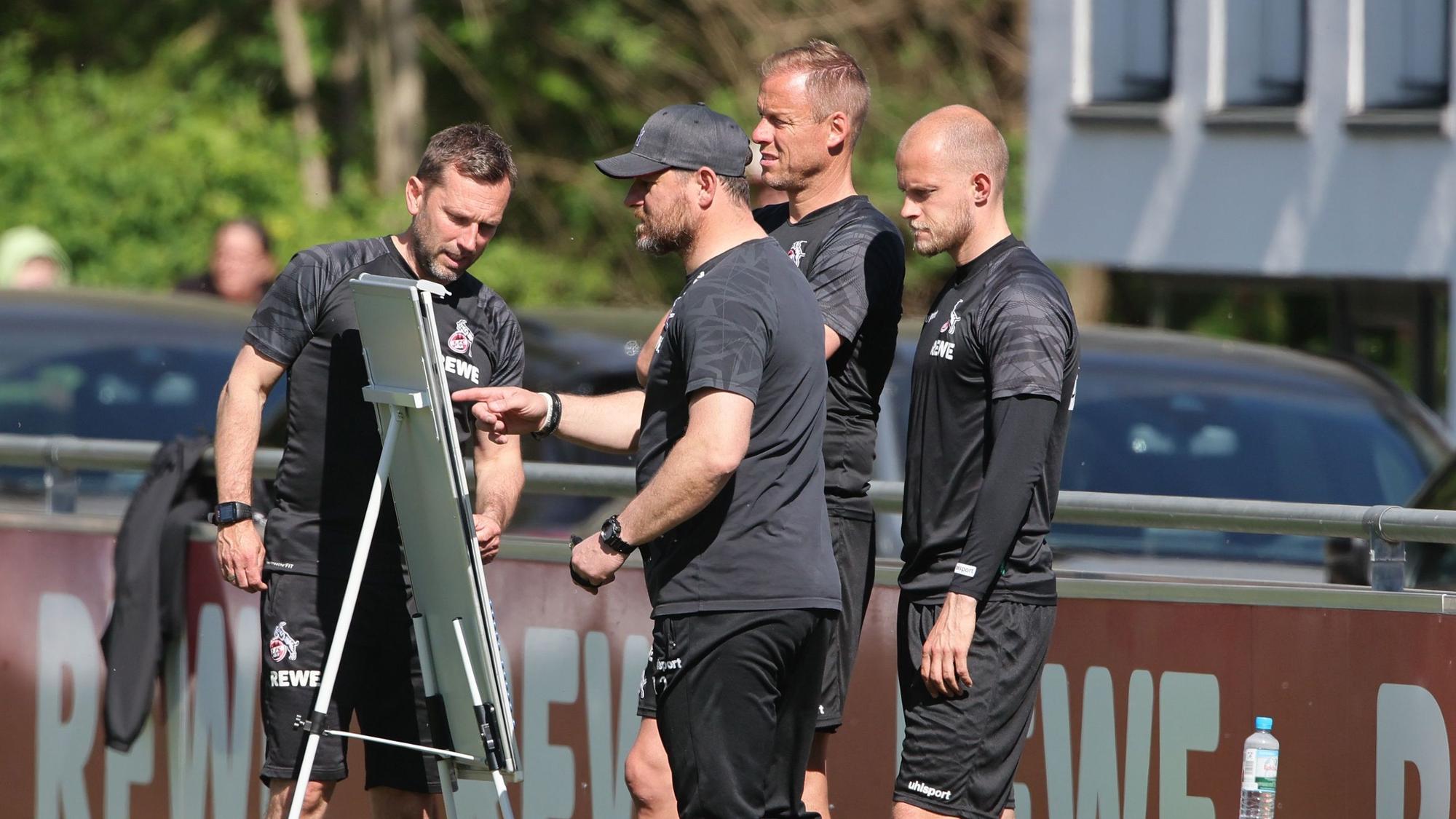 Steffen Baumgart und seine Co-Trainer gucken gemeinsam auf die Taktik-Tafel.