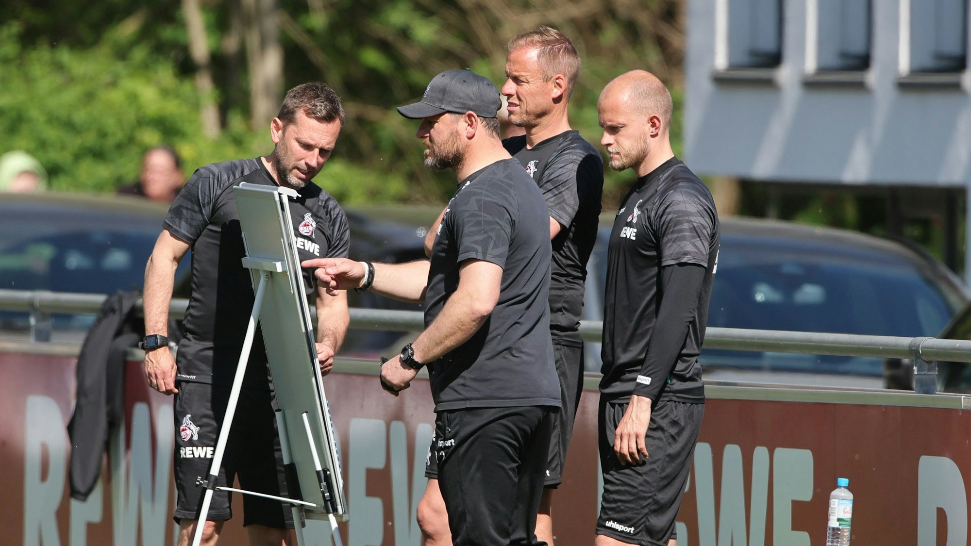 Steffen Baumgart und seine Co-Trainer gucken gemeinsam auf die Taktik-Tafel.