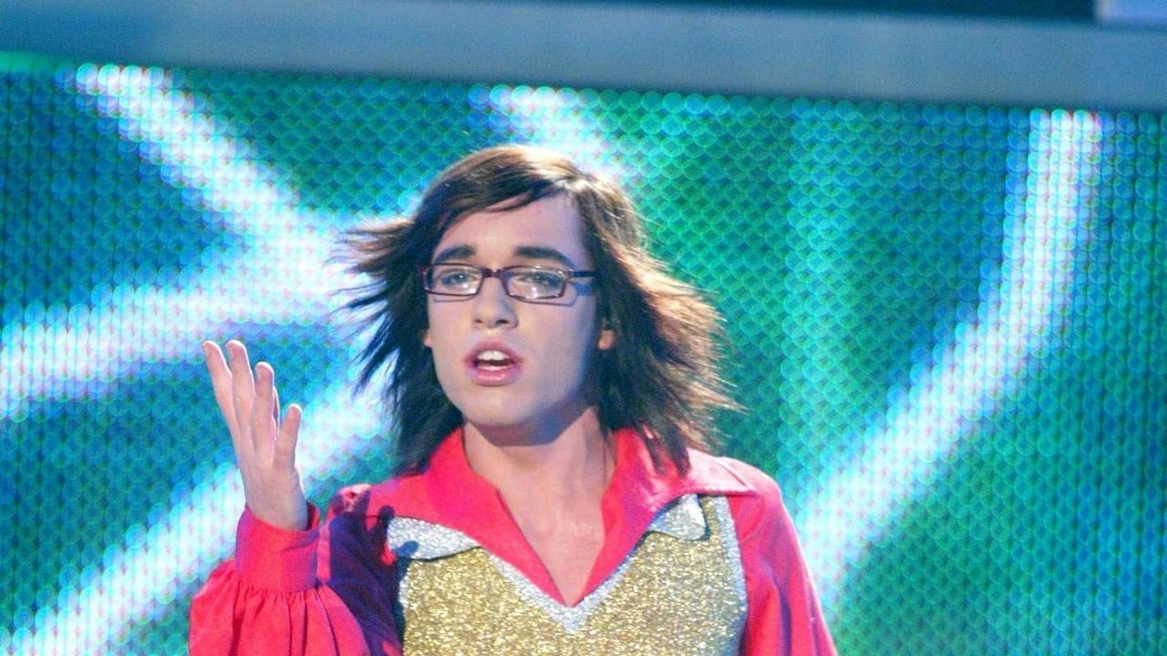 Ein junger Mann mit Brille, Sturmfrisur und Pailettenweste singt auf einer Bühne
