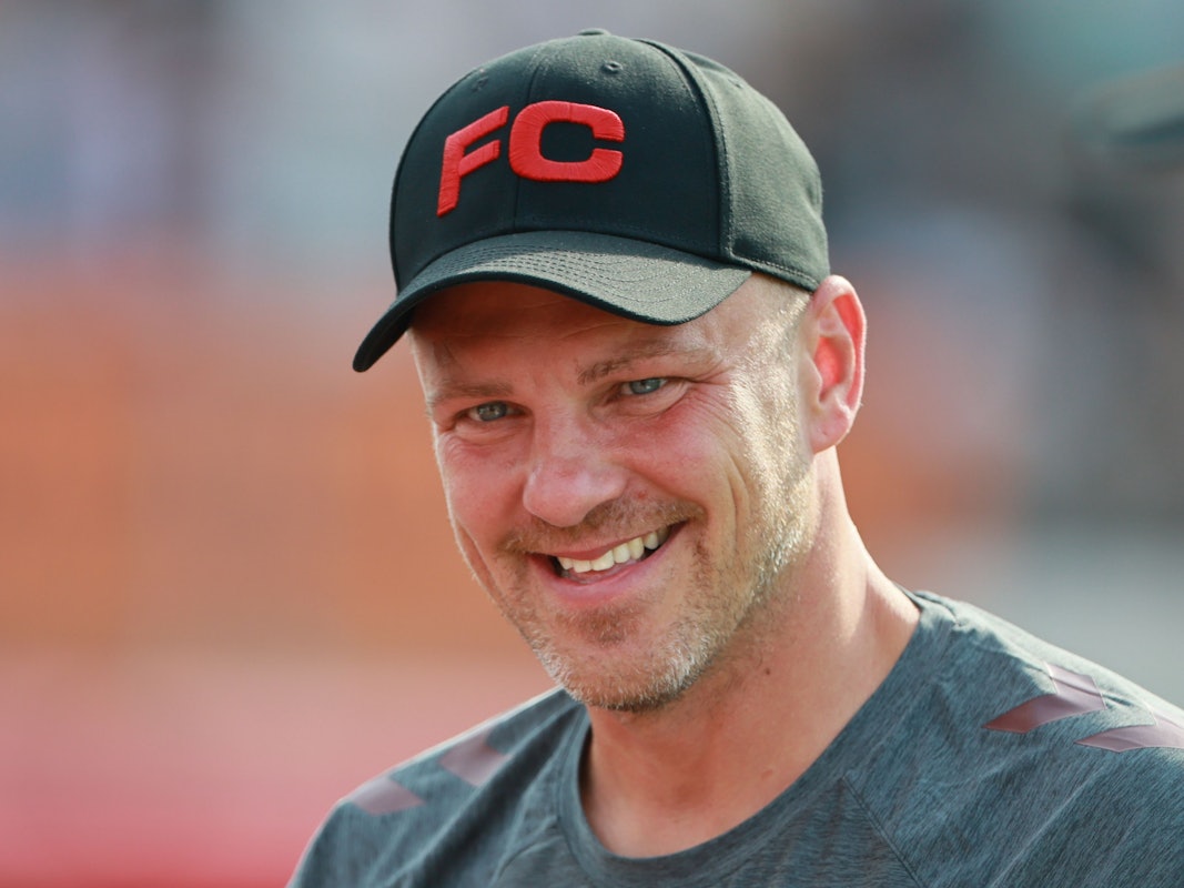 Lukas Kwasniok hat eine Kappe auf dem Kopf und lächelt.