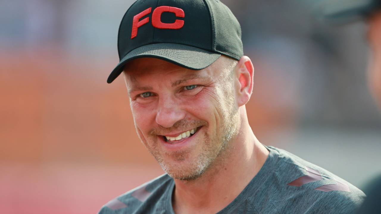 Lukas Kwasniok hat eine Kappe auf dem Kopf und lächelt.
