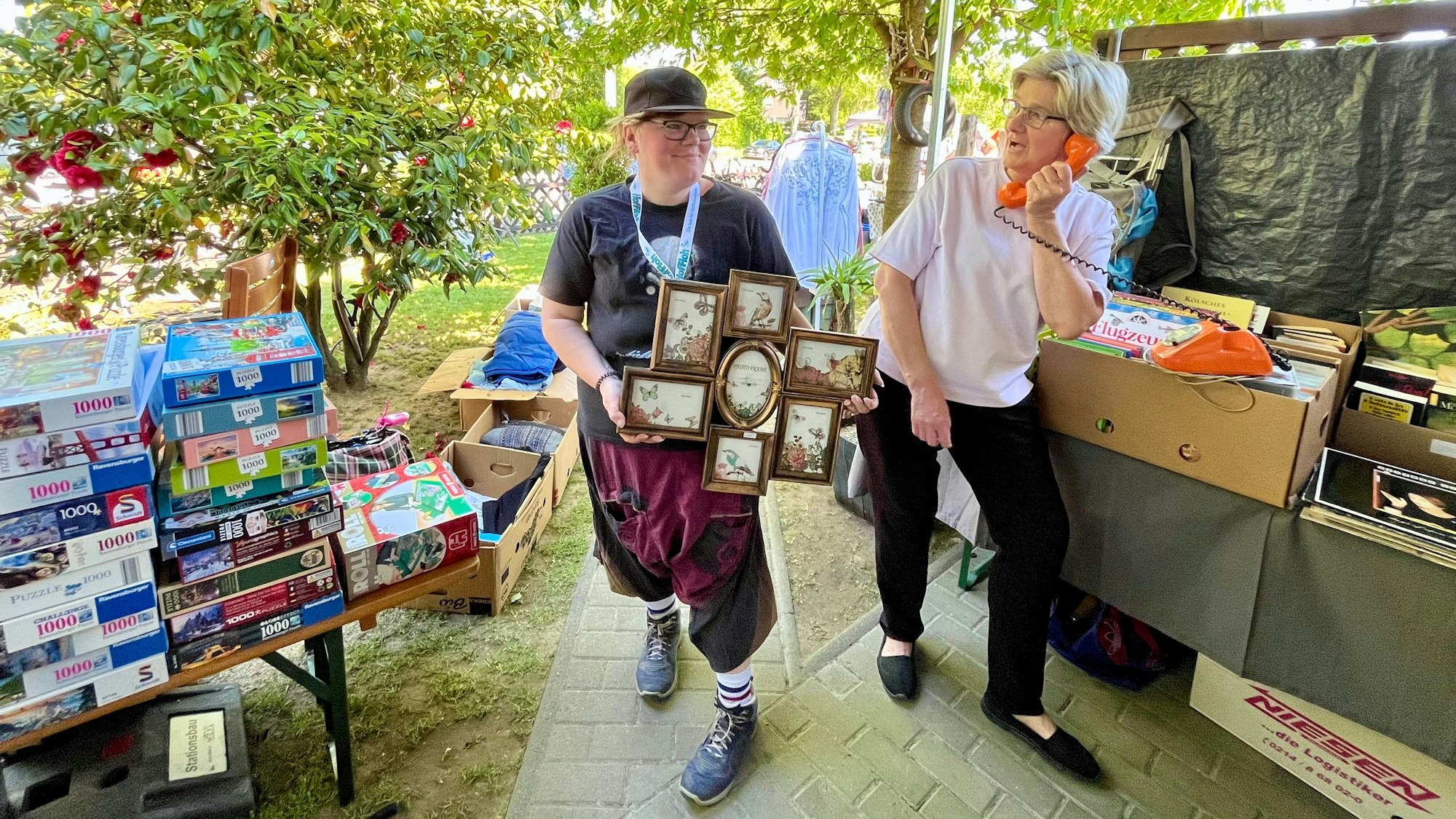 Zwei Frauen stehen zwischen Ständen mit Trödel.