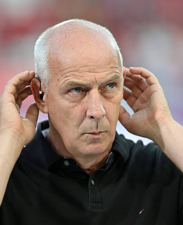 Mario Basler hält sich bei einer TV-Übertragung die Hände an die Ohren.