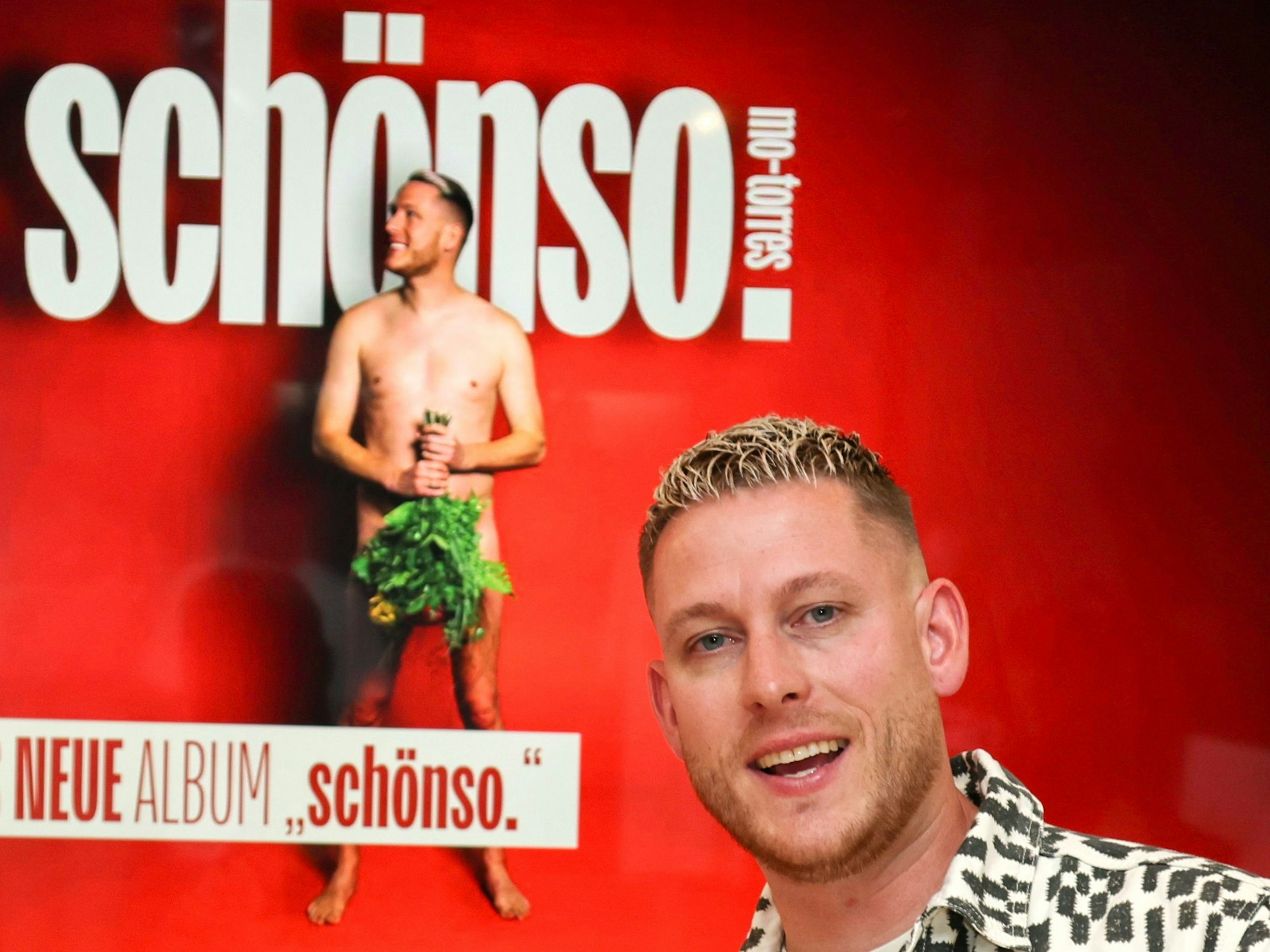 Mo-Torres vor dem Cover seines neuen Albums.