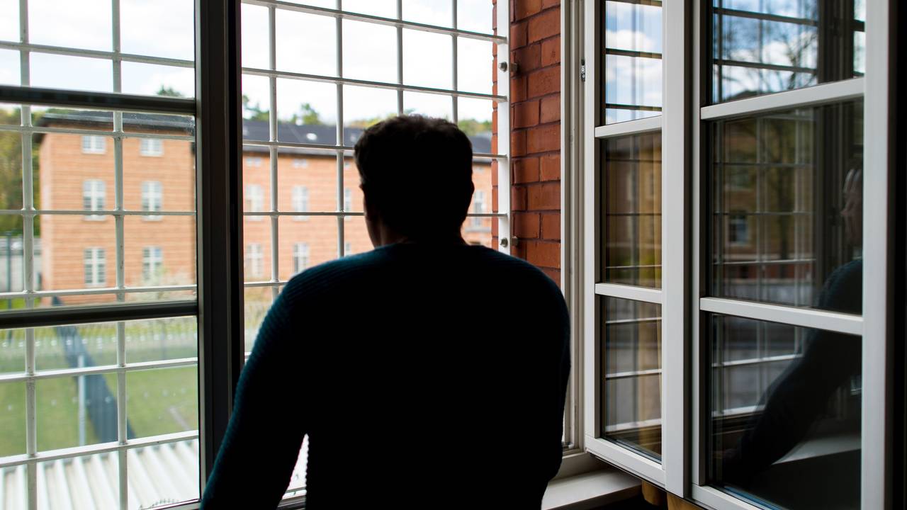 Ein Straftäter steht vor einem vergitterten Fenster in einer Klinik für Forensische Psychiatrie (Maßregelvollzug) auf dem Gelände eines Krankenhauses. (Symbolfoto)