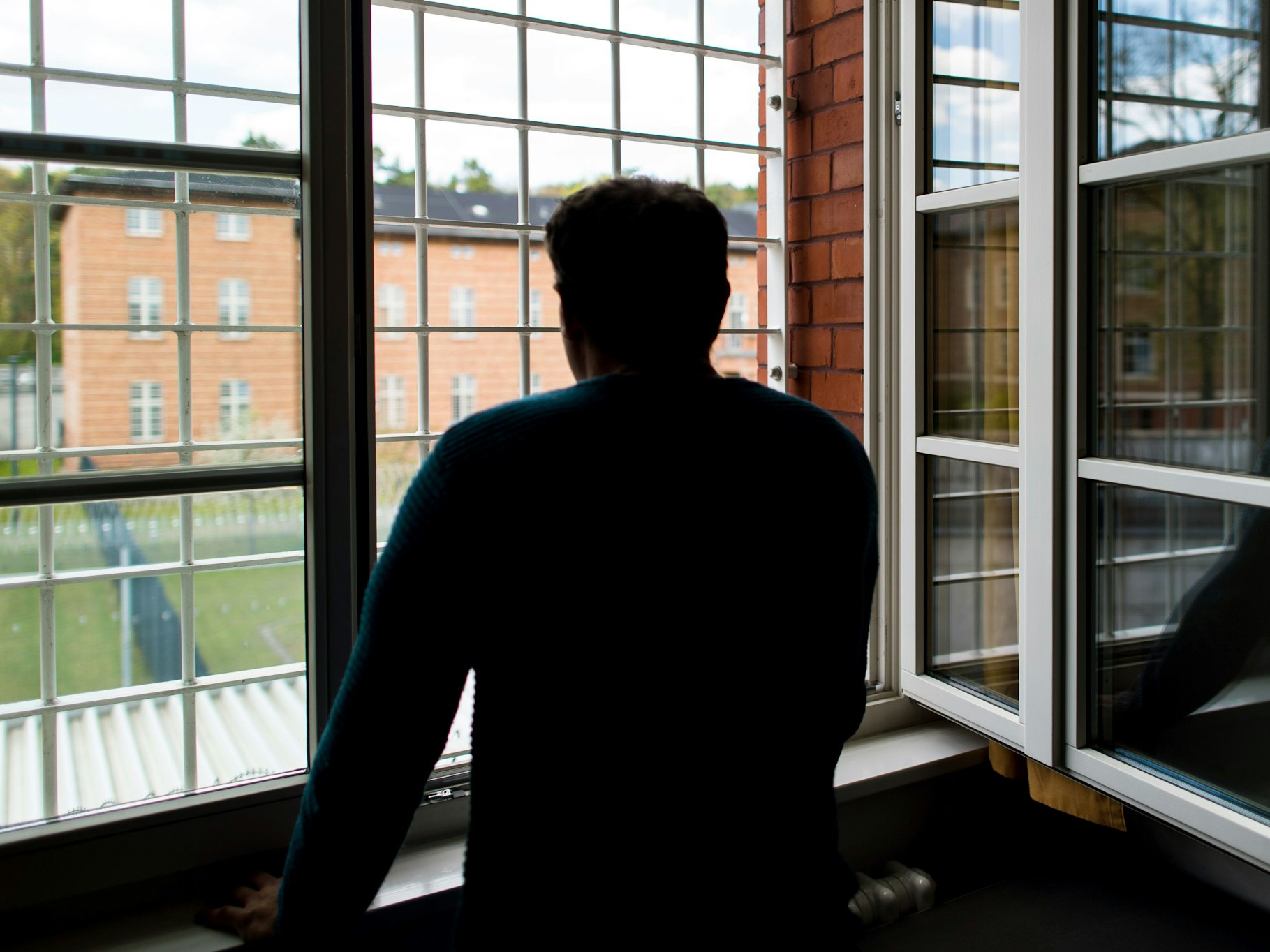 Die Polizei fahndet nach dem flüchtigen Patrick L.. Das Symbolfoto zeigt einenStraftäter vor einem vergitterten Fenster in einer Klinik für Forensische Psychiatrie (Maßregelvollzug).