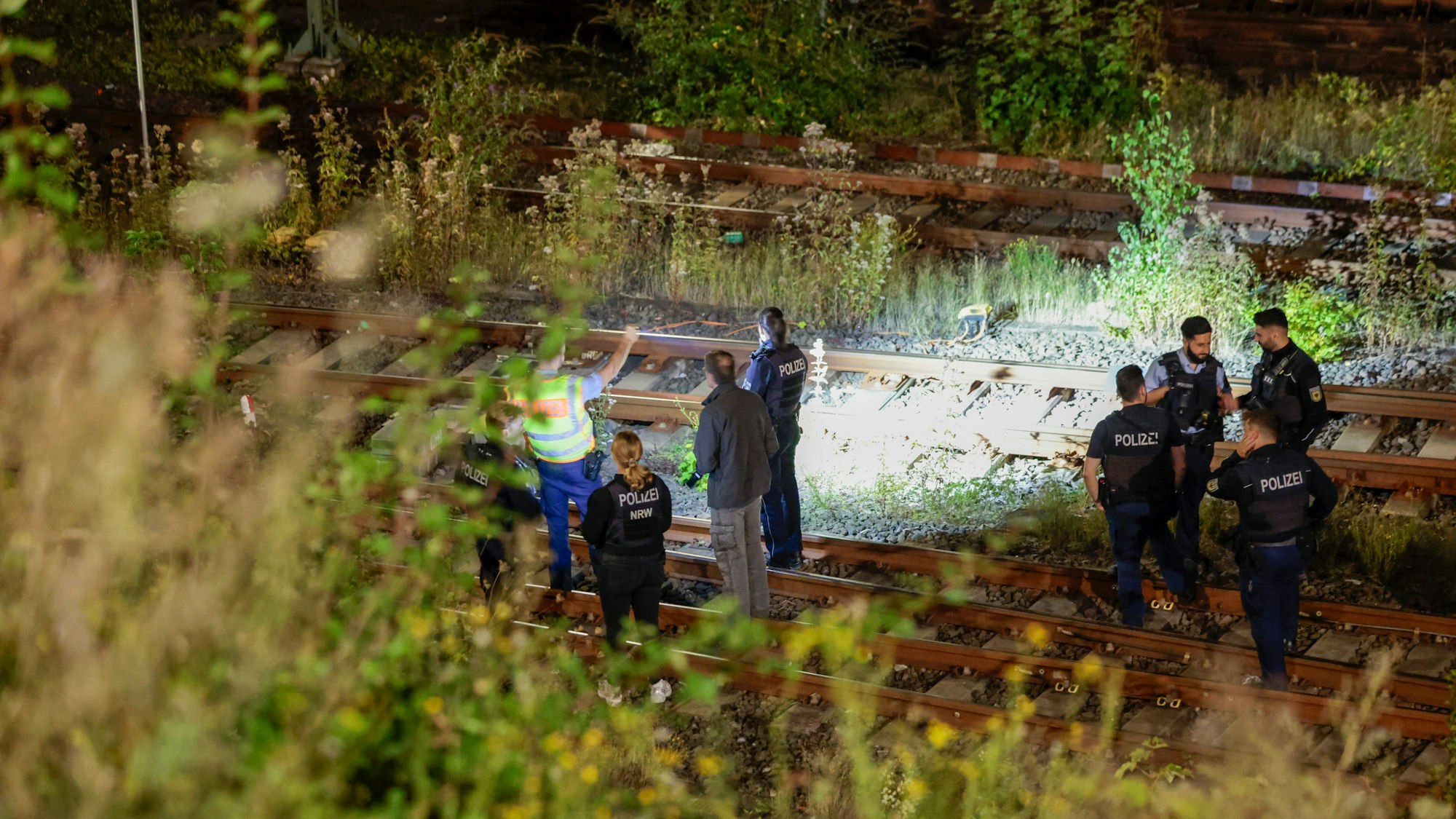 Polizeikräfte stehen nachts an Bahngleisen.