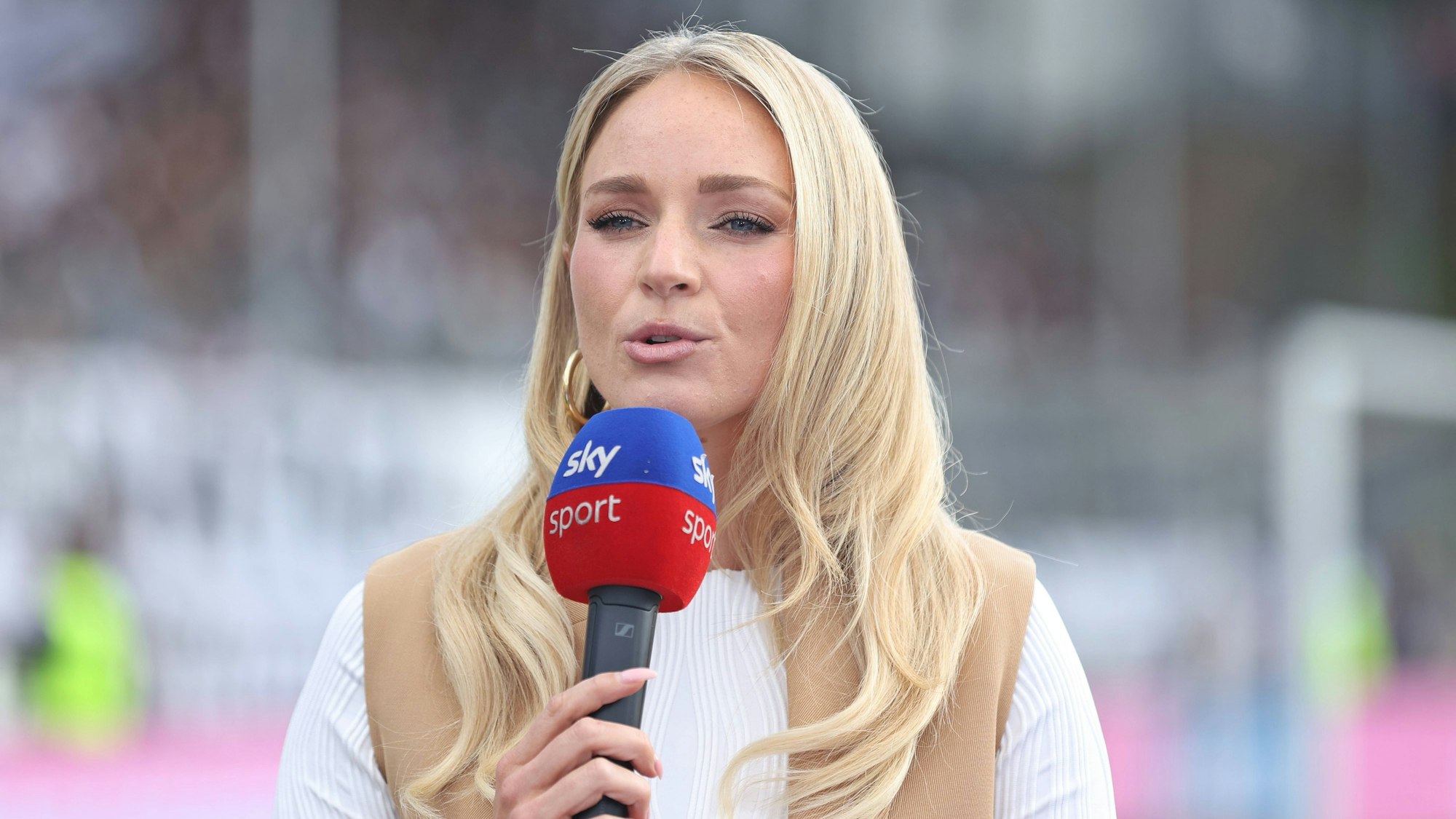 Sky-Moderatorin Katharina Kleinfeldt spricht mit einem Mikrofon in der Hand.