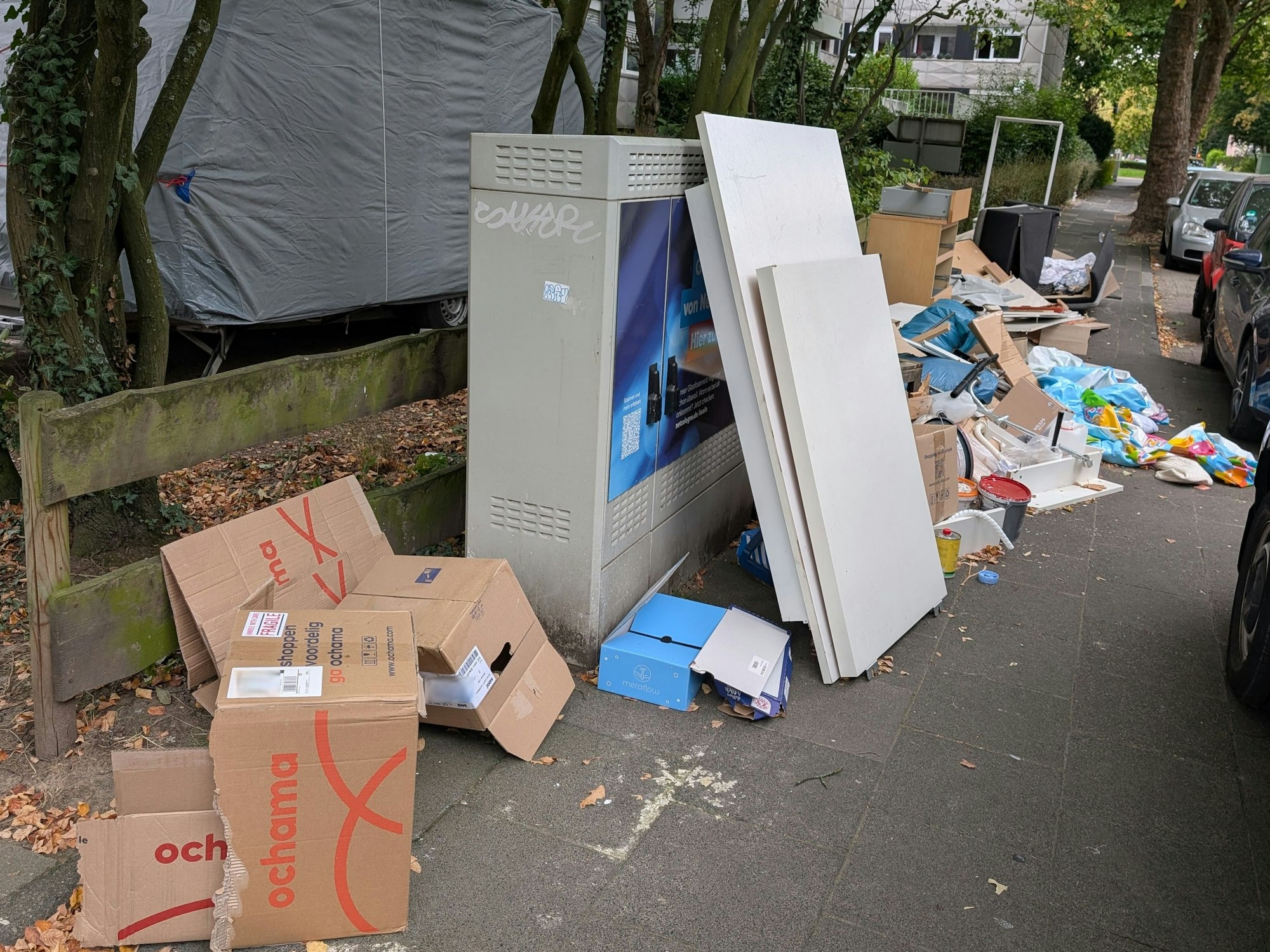 Auf einem Gehweg liegen entsorgte Einrichtungsgegenstände, Bretter, Plastikmüll und zerfetzte Kartons.