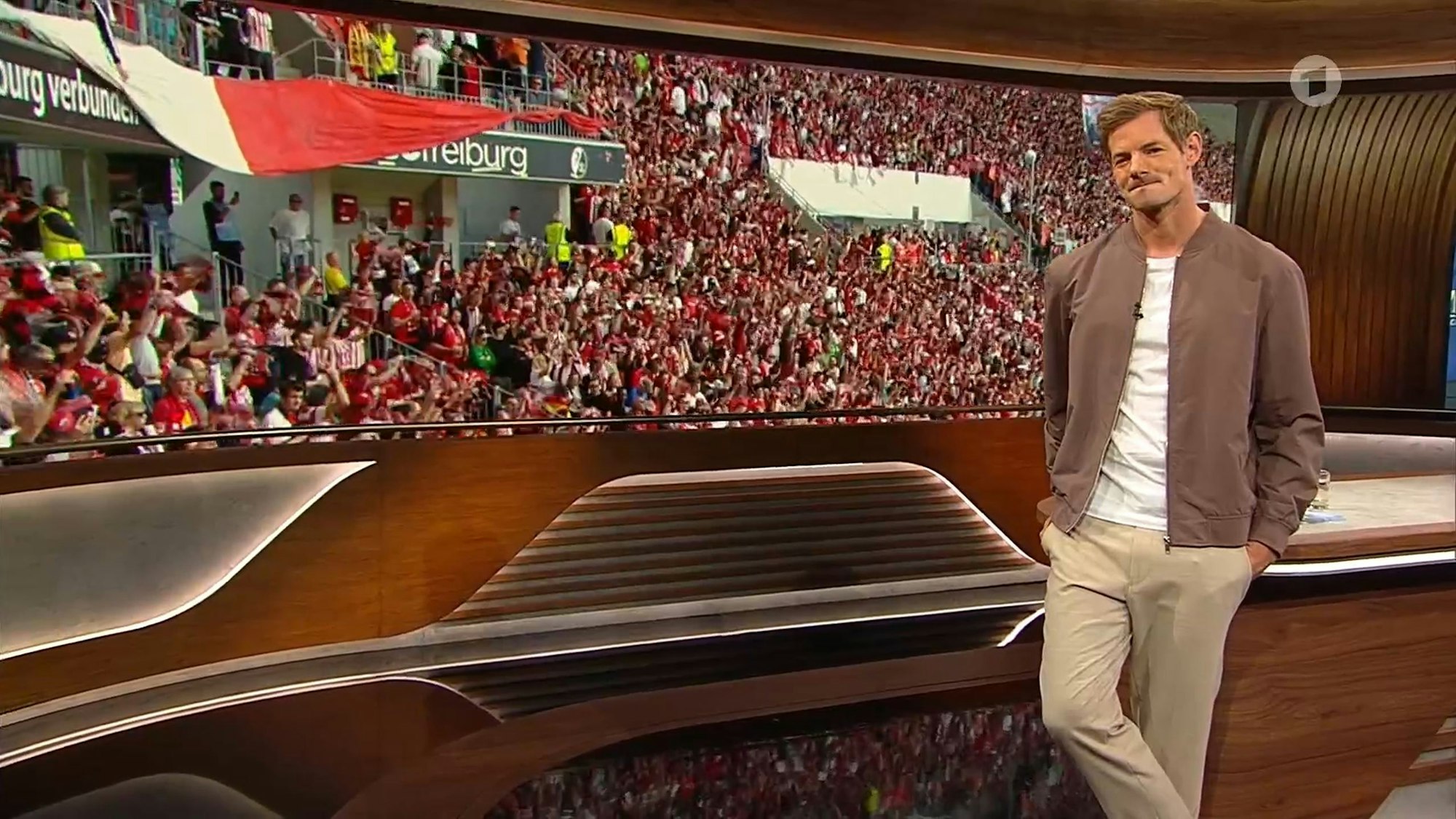 Alex Schlüter steht wartend vor dem Screen.