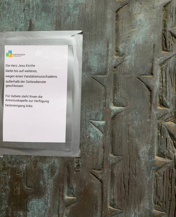 An einer Kirchentür hängt ein Zettel mit dem Hinweis: Wegen Vandalismusschäden bleibt die Herz-Jesu-Kirche in Euskirchen außerhalb der Gottesdienstzeiten geschlossen.