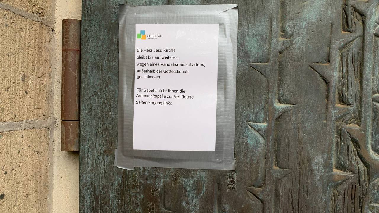 An einer Kirchentür hängt ein Zettel mit dem Hinweis: Wegen Vandalismusschäden bleibt die Herz-Jesu-Kirche in Euskirchen außerhalb der Gottesdienstzeiten geschlossen.