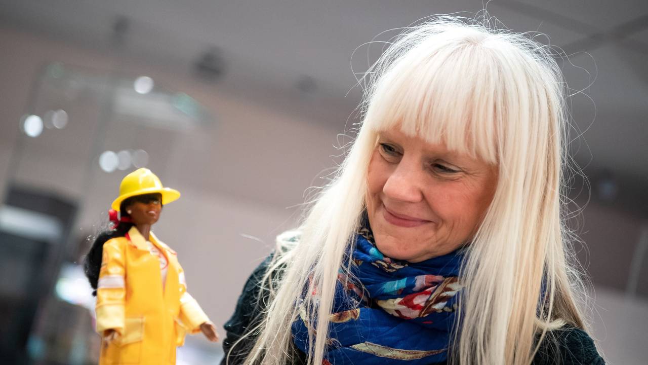 Eine Frau hält eine Barbie-Puppe in der Hand.