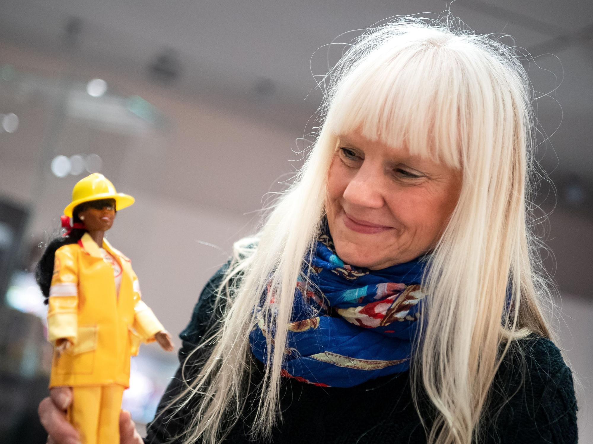 Eine Frau hält eine Barbie-Puppe in der Hand.
