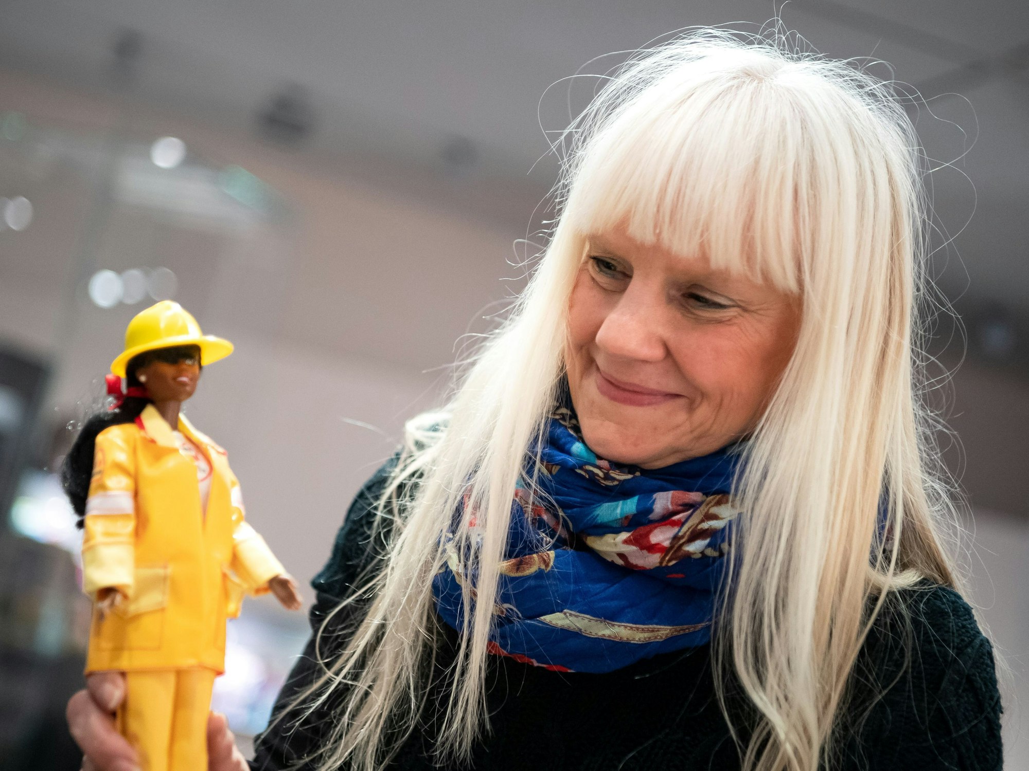 Eine Frau hält eine Barbie-Puppe in der Hand.