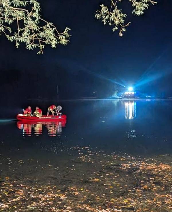 Einsatzkräfte der Feuerwehr sind in einem Boot auf einem See unterwegs.