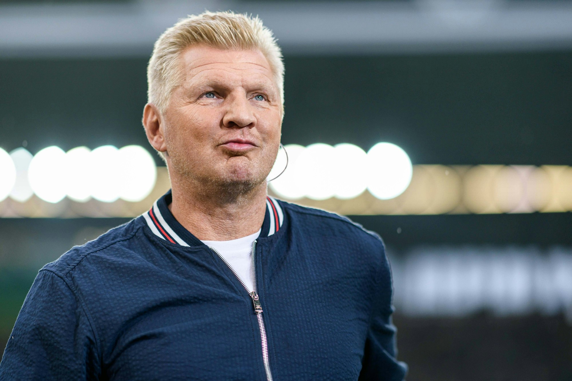 Stefan Effenberg trägt einen Kopfhörer im Ohr.