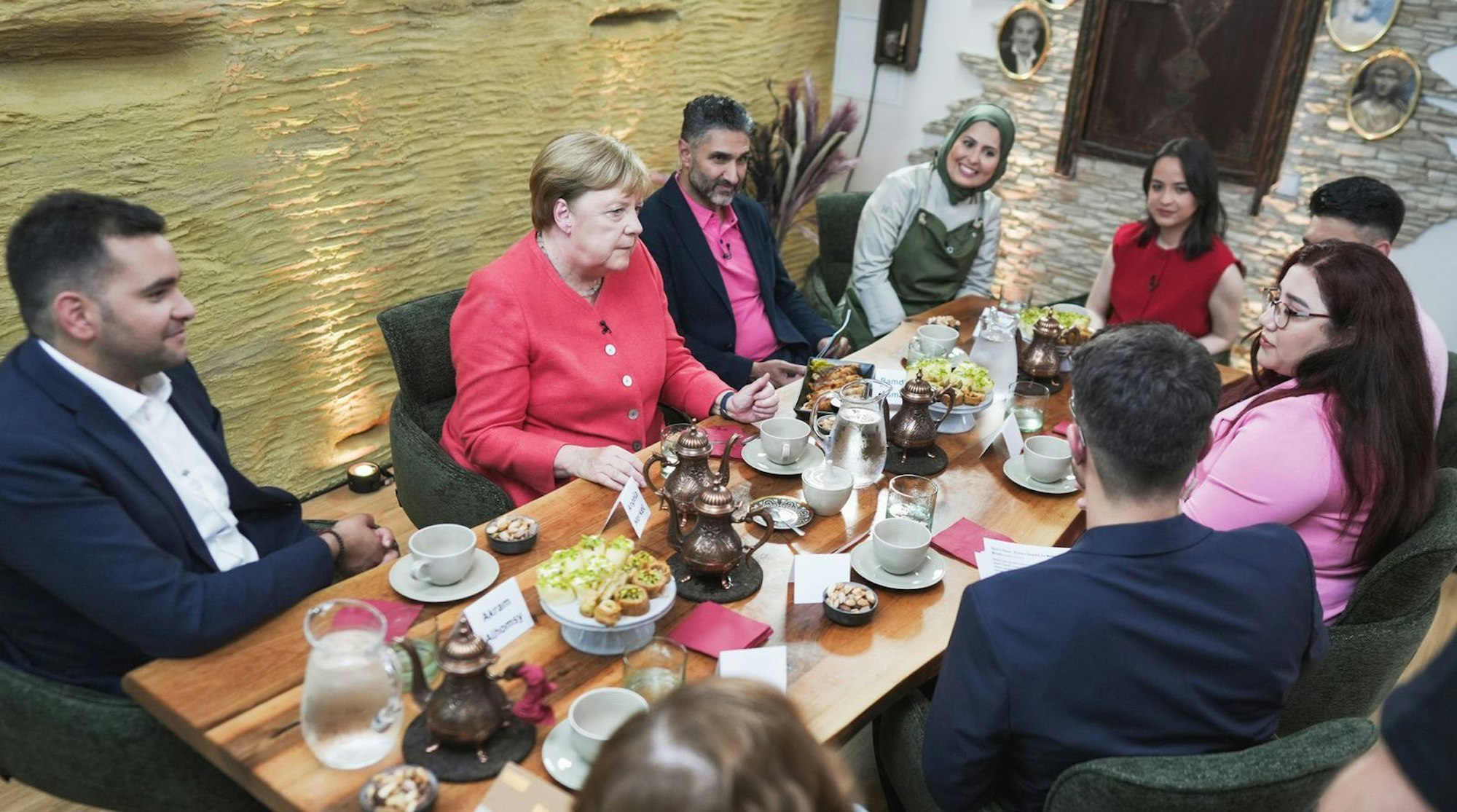 In einem syrischen Restaurant in Berlin spricht Angela Merkel mit Menschen, die einst nach Deutschland flüchteten. (Bild: WDR/Mirko Polo)