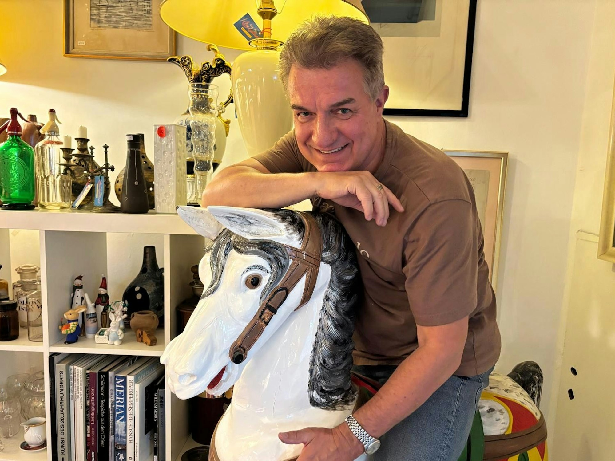 Linus sitzt in seinem Laden auf einem Schaukelpferd.