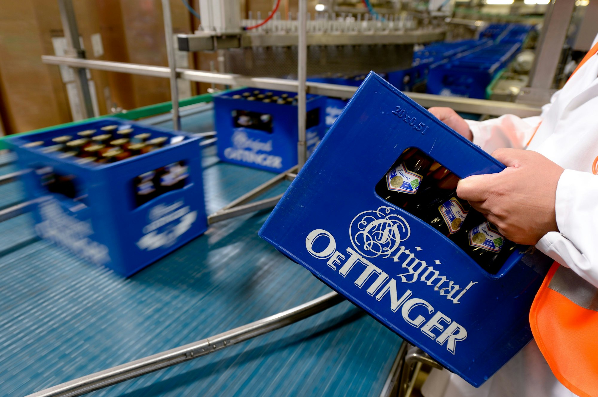 Eine Kiste Oettinger-Bier wird in der Oettinger Brauerei in Braunschweig auf ein Transportband gestellt.