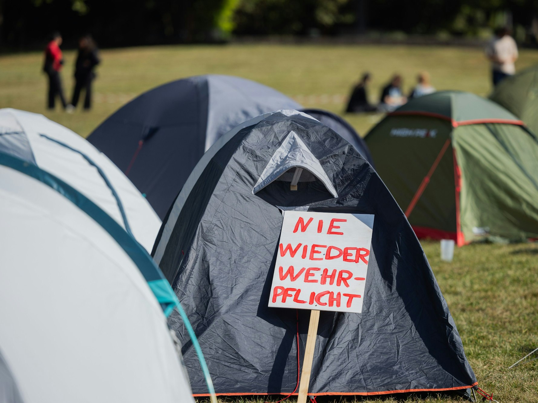 „Nie wieder Wehrpflicht“ steht auf einem Schild im Protestcamp des Bündnisses ‚Rheinmetall Entwaffnen‘. Unter dem Motto ‚Mach was wirklich zählt! Rheinmetall entwaffnen‘ werden vom 26. bis zum 31. August rund 1.000 Teilnehmer erwartet.