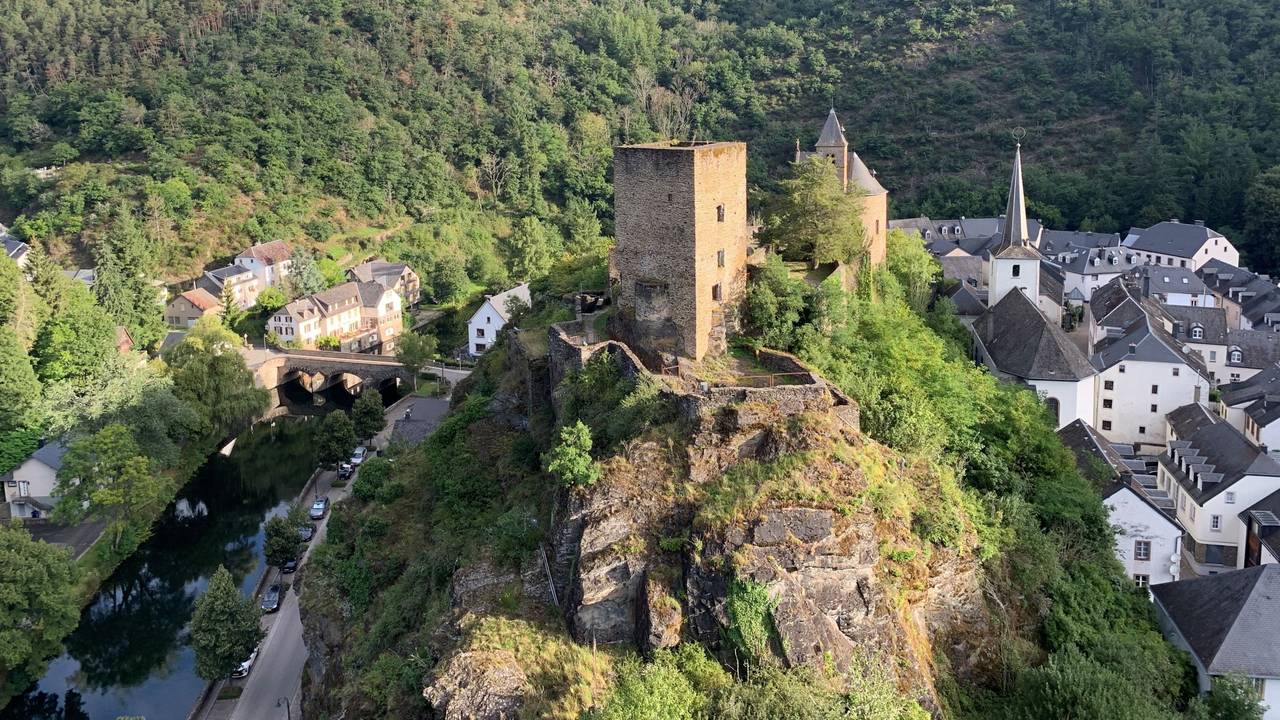 Eine trutzige Burg steht auf einem einzelnen Berg über einer kleinen Stadt