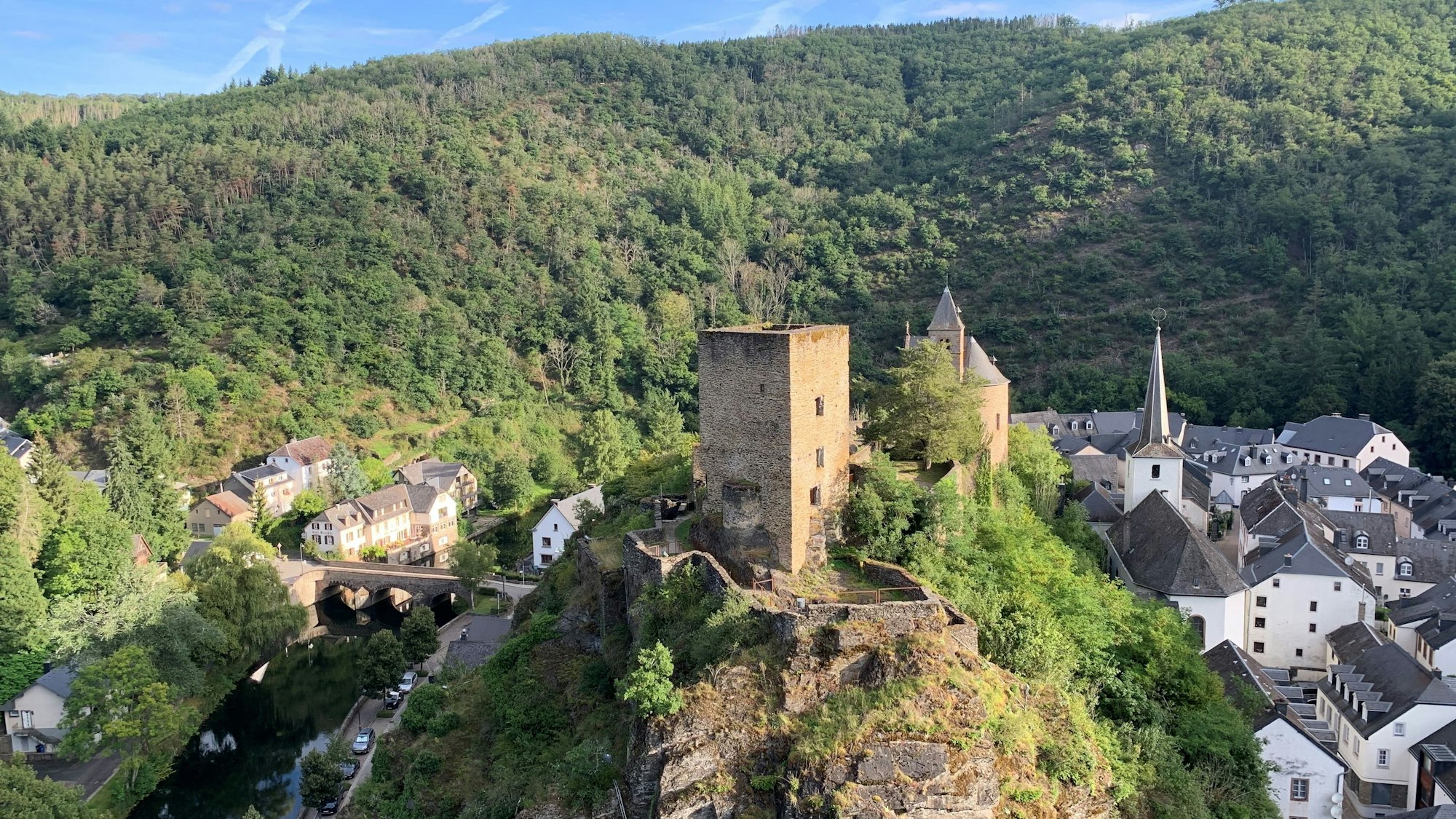 Eine trutzige Burg steht auf einem einzelnen Berg über einer kleinen Stadt