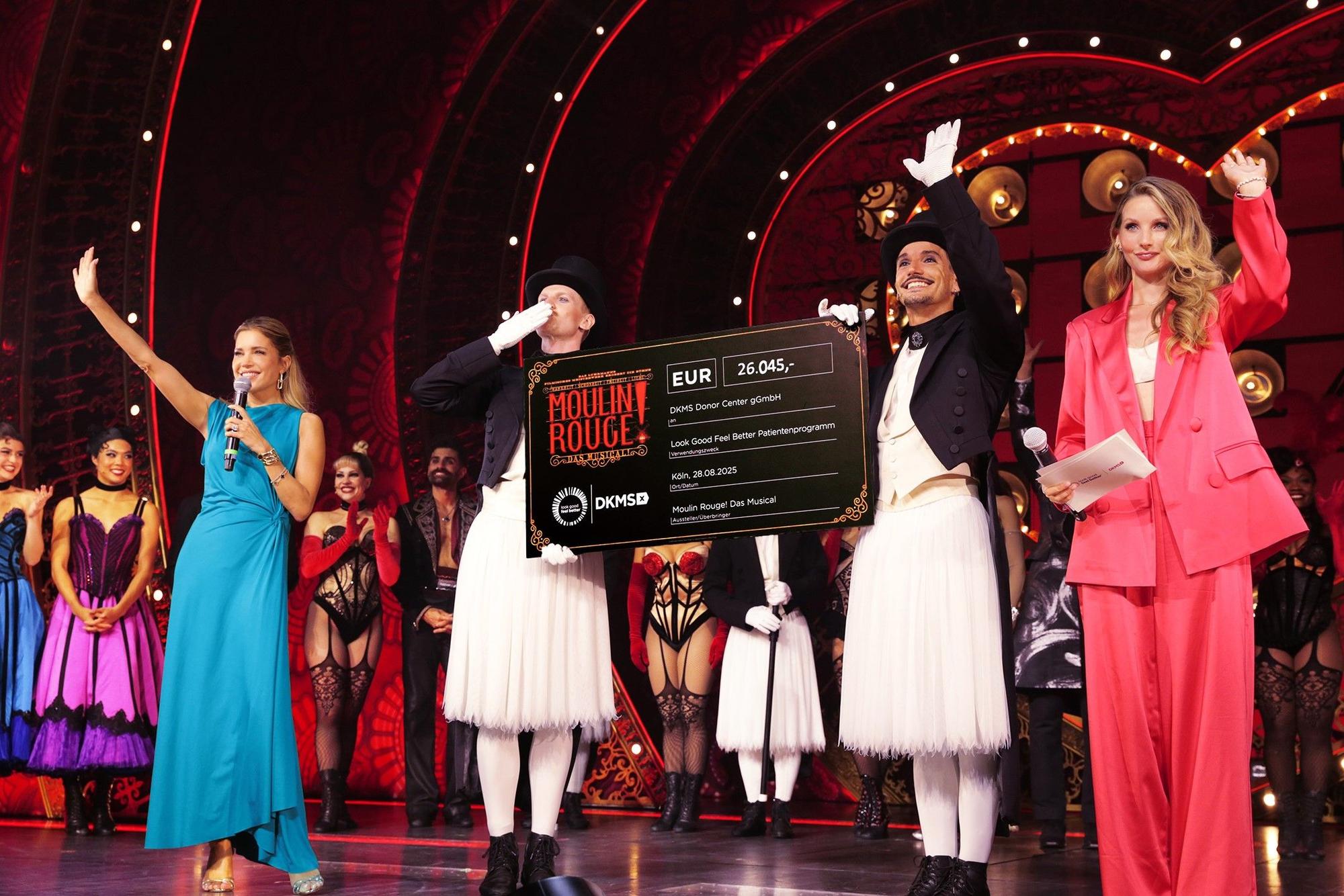 Sylvie Meis (l.), Anna Hiltrop (r.) und der Cast von Moulin Rouge bei der Scheckübergabe.