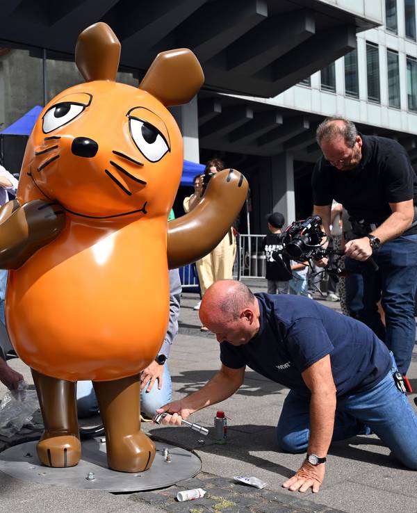 Techniker schrauben die reparierte Maus-Figur auf ihrem angestammten Platz fest. Unbekannte hatten die Maus Ende Juli angezündet, so dass sie beschädigt wurde und repariert werden musste.