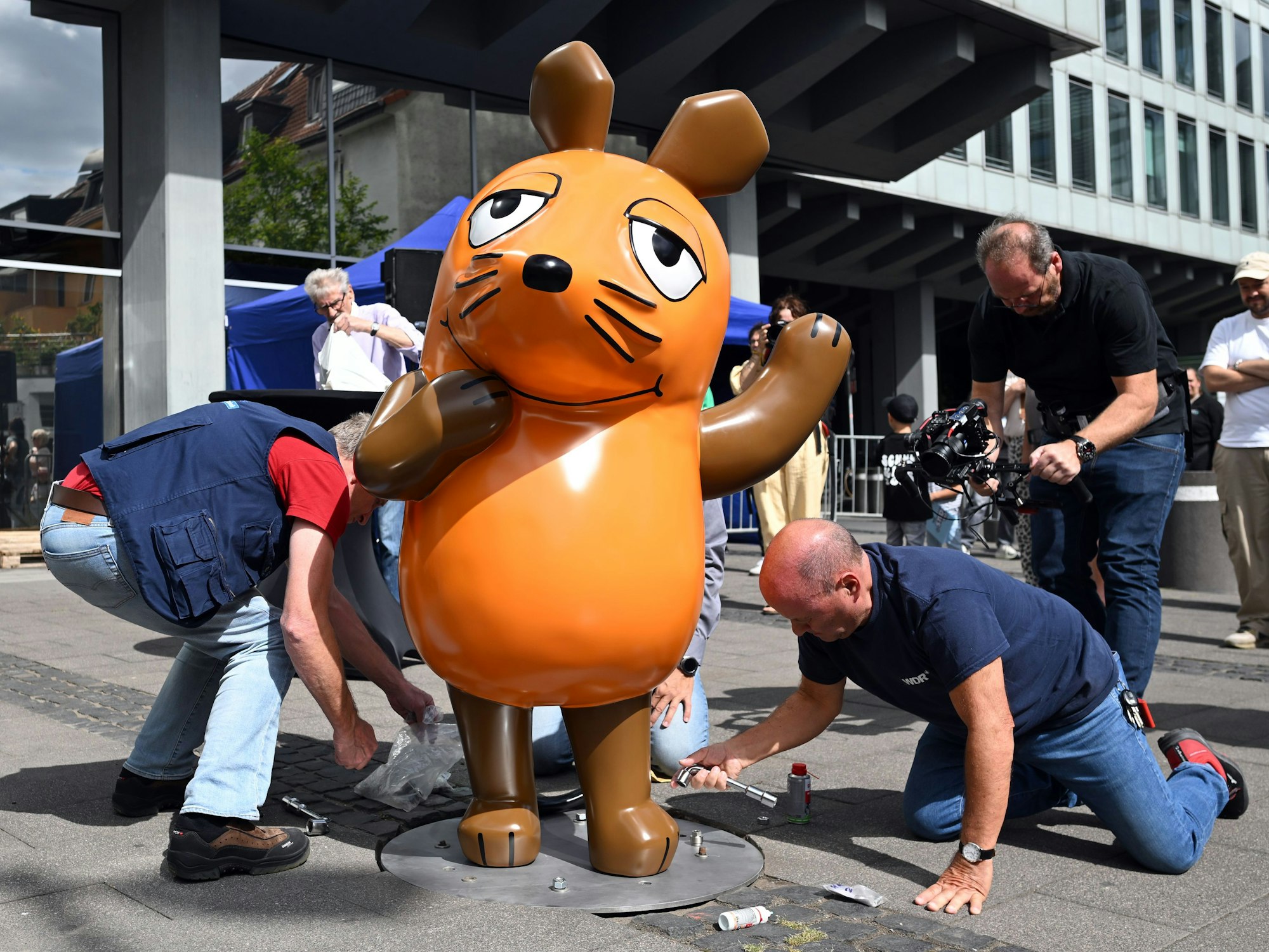 Techniker schrauben die reparierte Maus-Figur auf ihrem angestammten Platz fest. Unbekannte hatten die Maus Ende Juli angezündet, so dass sie beschädigt wurde und repariert werden musste.