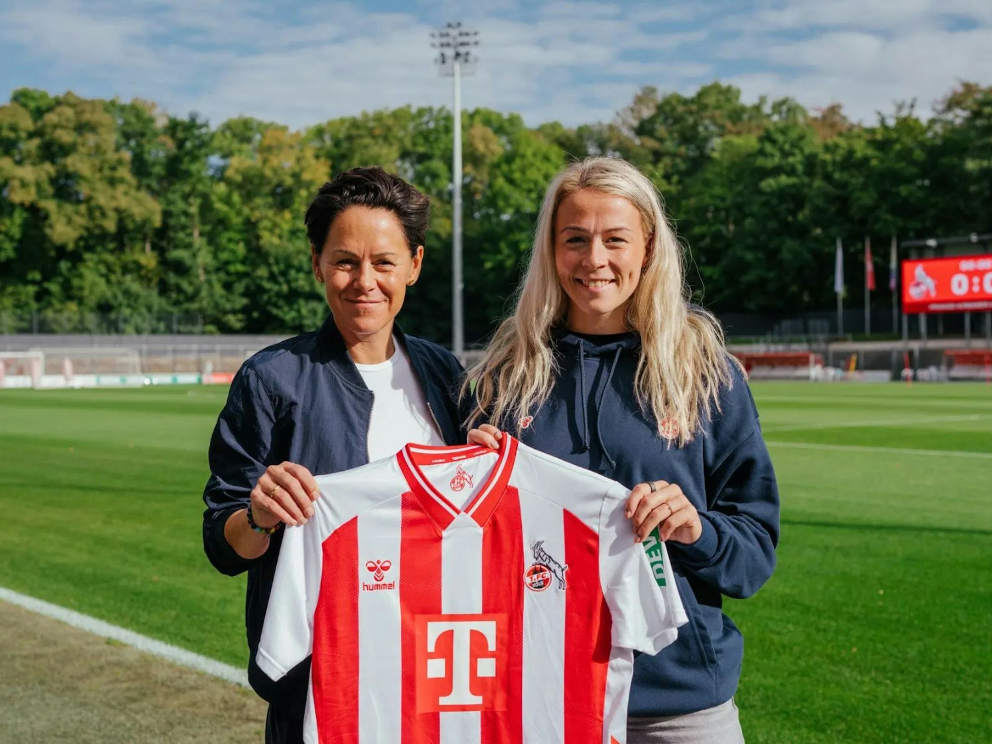 Sandra Maria Jessen und Nicole Bender-Rummler halten für ein Foto ein FC-Trikot hoch.