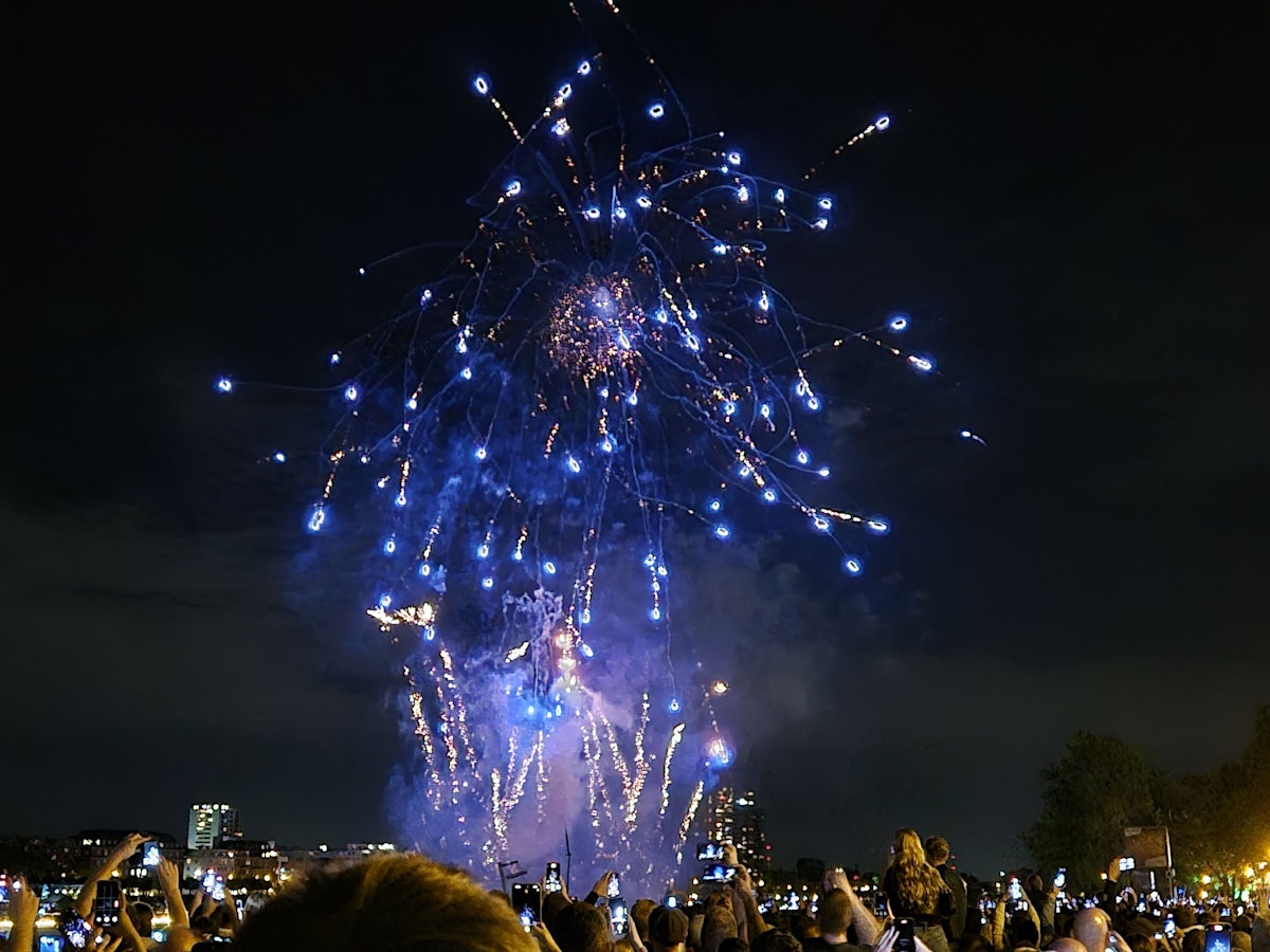 Besucher sehen sich ein Feuerwerk an. Das Festival Kölner Lichter mit Musik und Feuerwerk am Rhein.