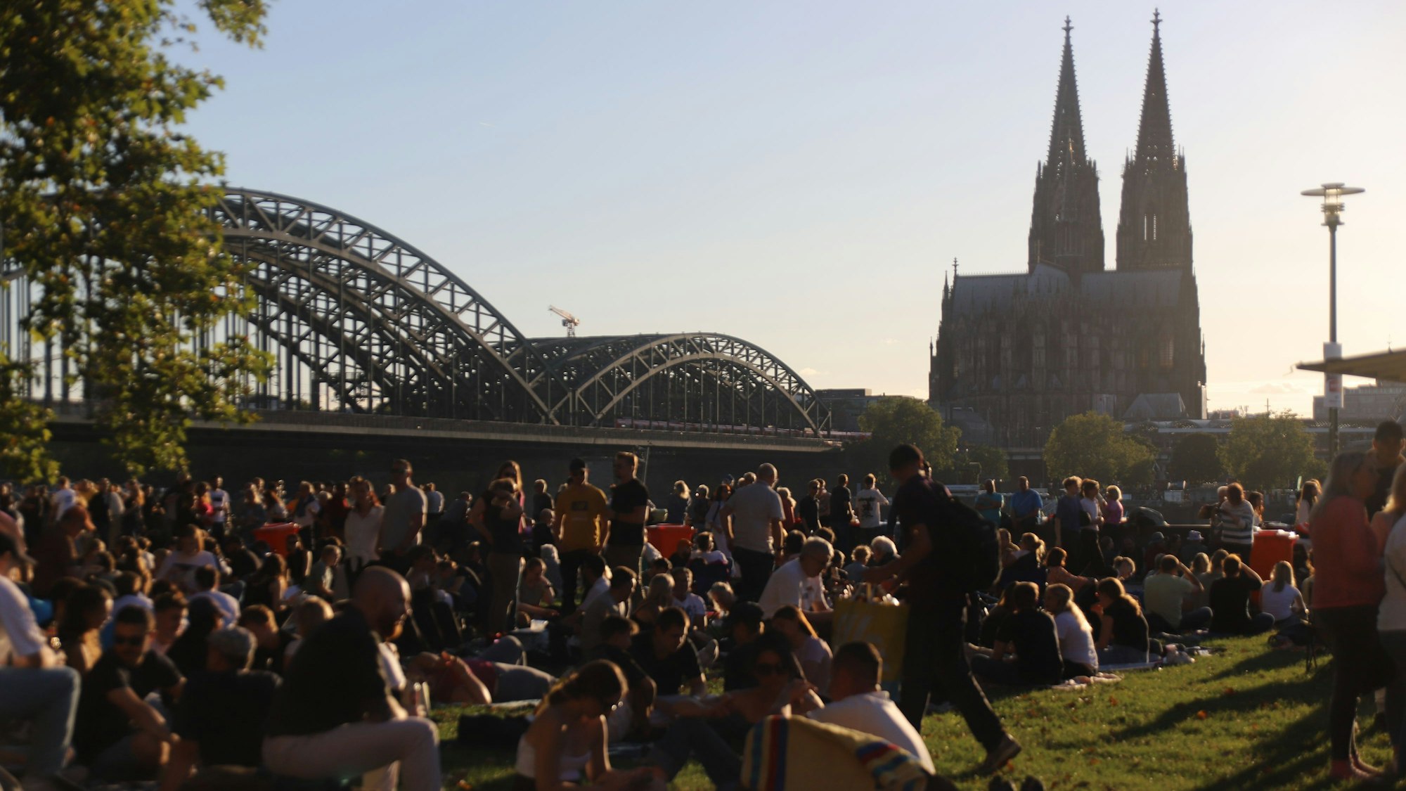 Besucher sitzen auf einer Wiese mit Blick auf den Dom und das Feuerwerk.