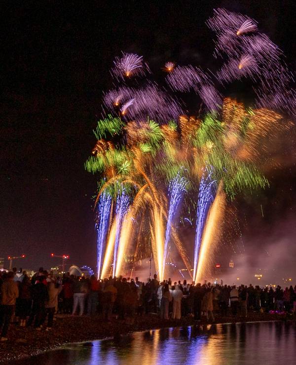 Menschen besuchen im Kölner Rheinpark das größte musiksynchrone Feuerwerk Europas.