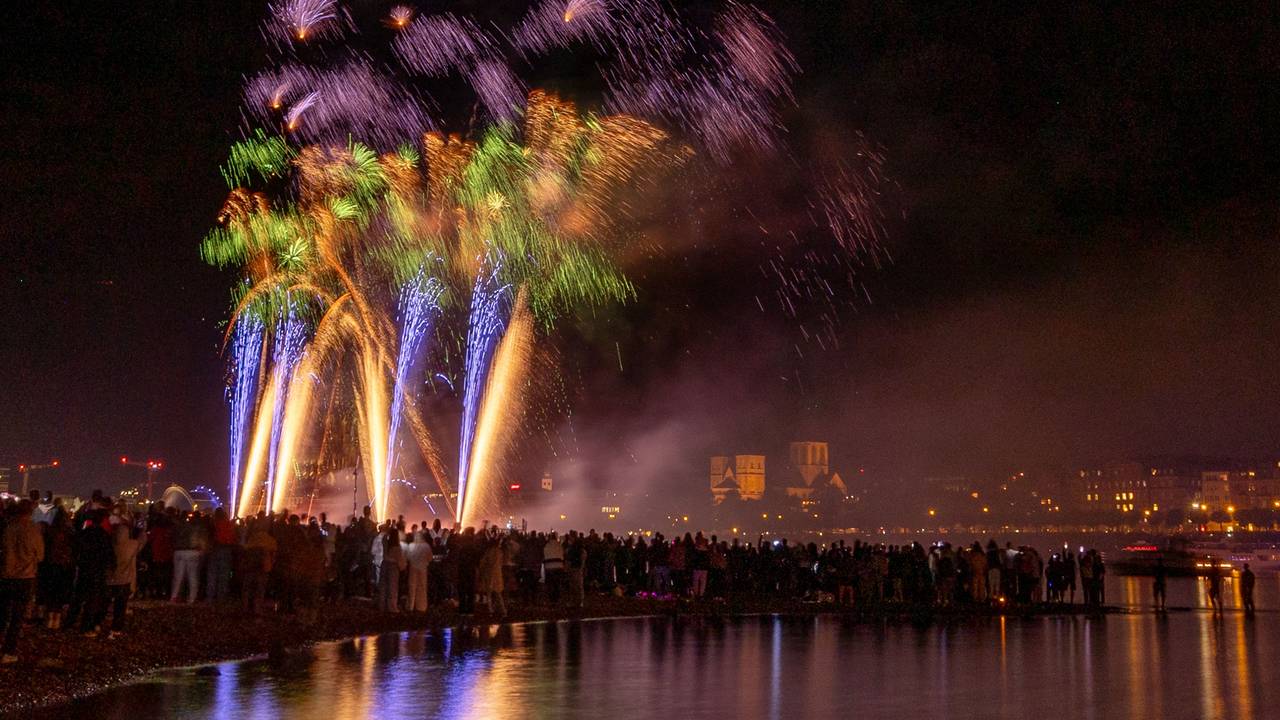 Menschen besuchen im Kölner Rheinpark das größte musiksynchrone Feuerwerk Europas.