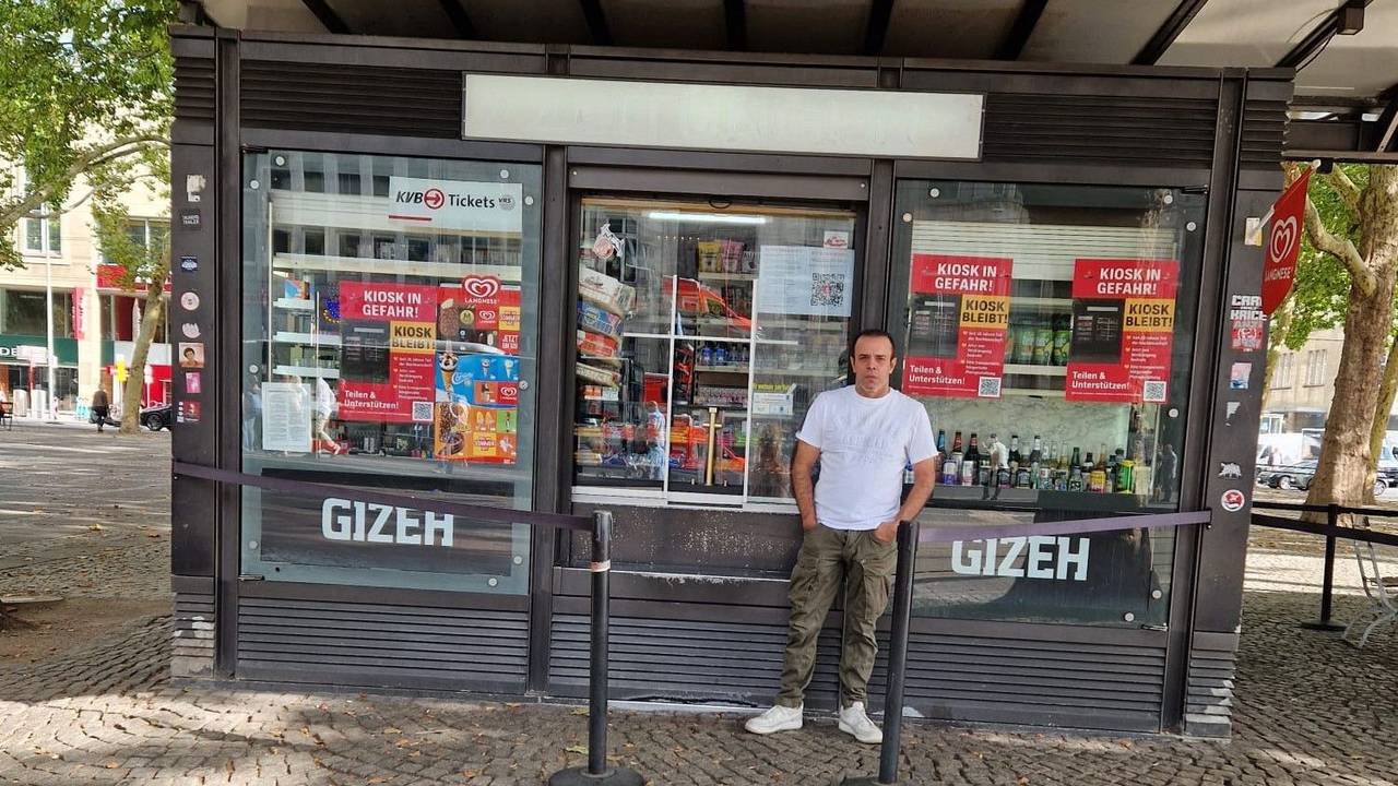 Ein Mann steht vor einem Kiosk.