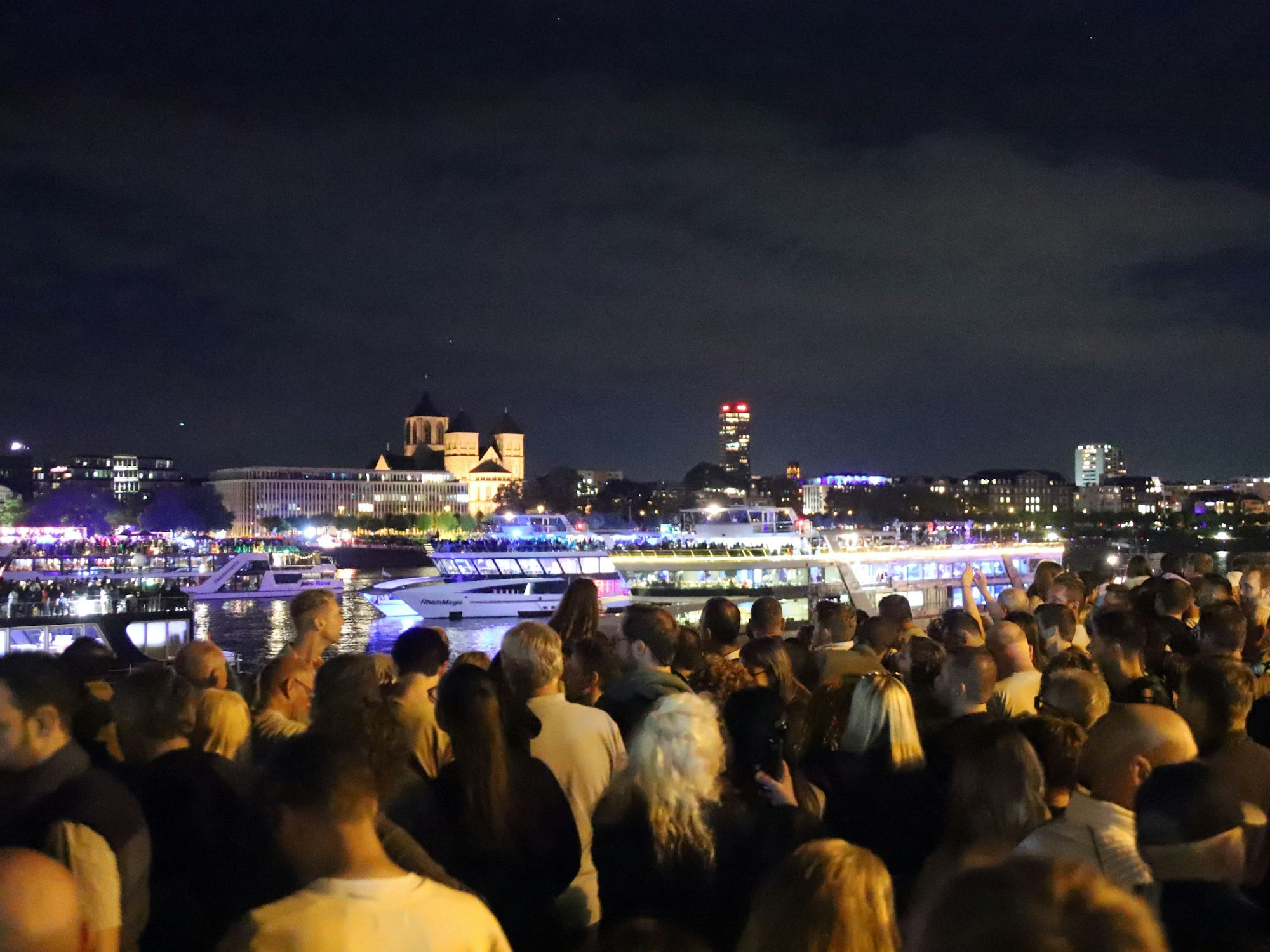 Besucher schauen vom Rheinufer auf die ankommenden Schiffe beim Festival Kölner Lichter.
