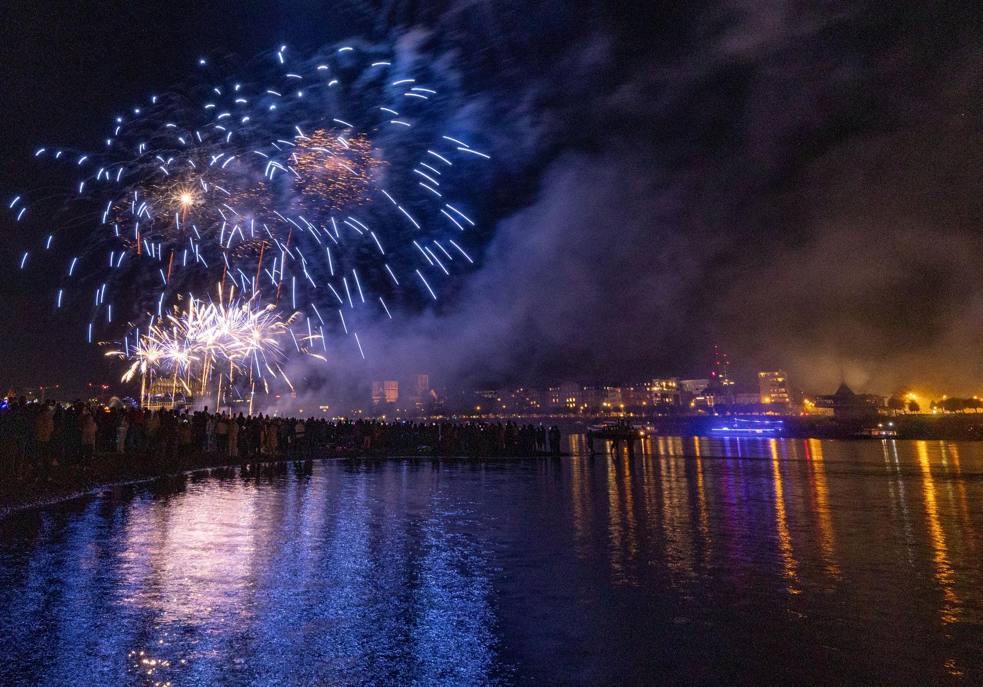 Menschen besuchen im Kölner Rheinpark das größte musiksynchrone Feuerwerk Europas.