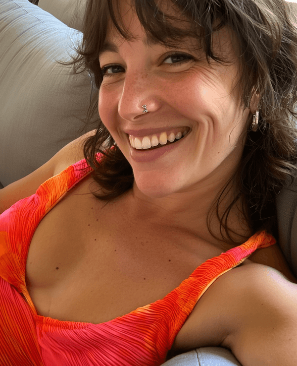 Lächelnde Frau sitzt auf einer Couch und schießt ein Selfie von sich.
