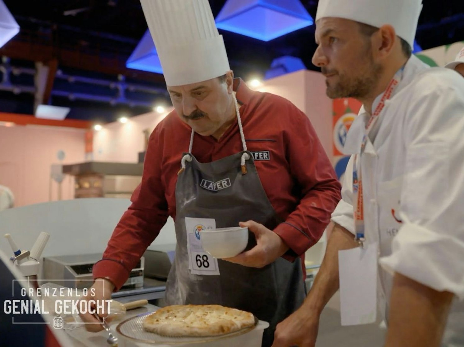 Der erste Wettkampf. Steffen Henssler (rechts) und Johann Lafer treten in der Klasse „Pizza a due“ im Team an. Kommt ihre ausgefallene Idee bei der Jury an? Sie machen „Pizza Carbonara“. (Bild: RTL)