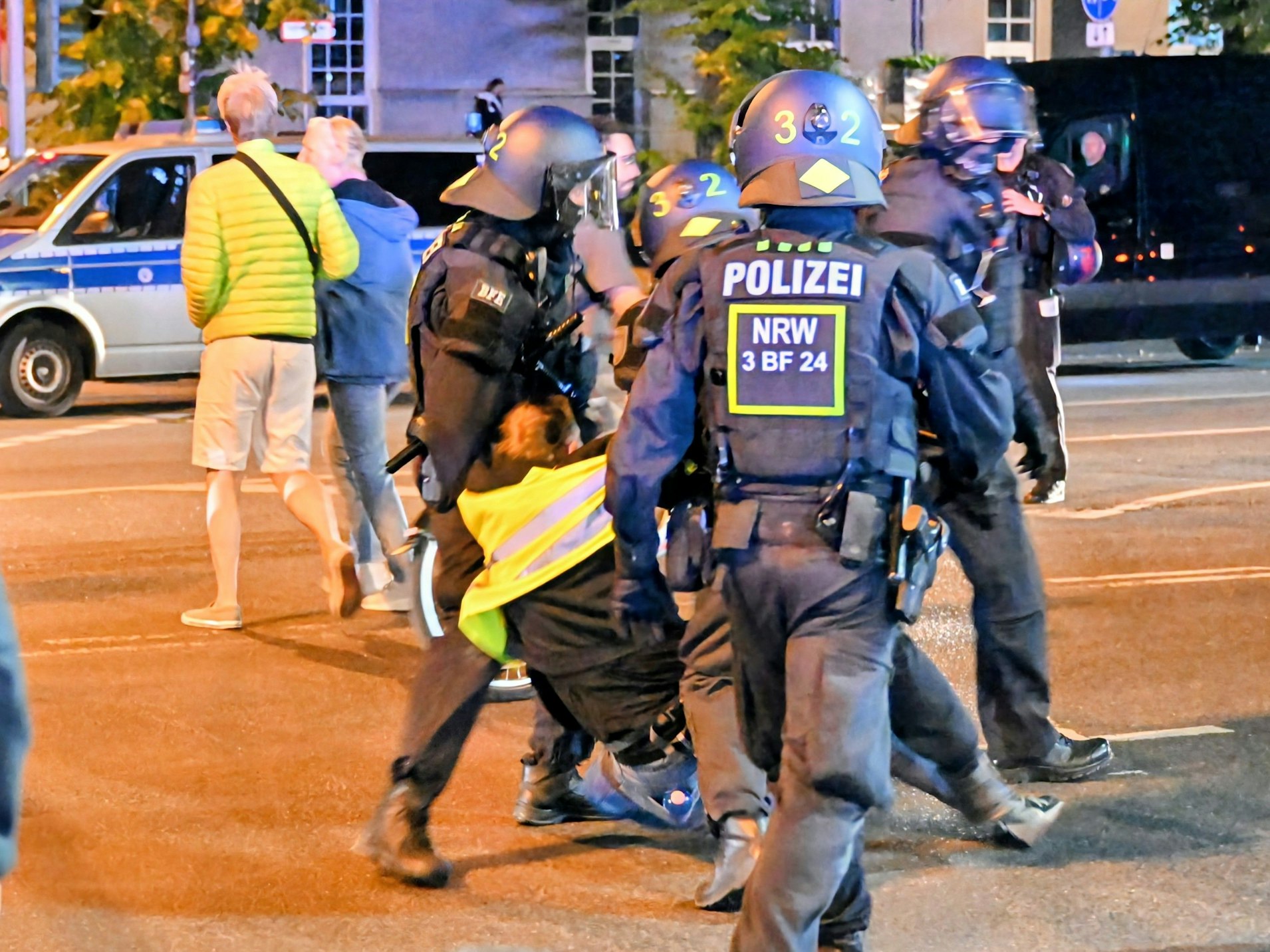 Polizeikräfte führen einen Mann ab, der sich mit den Füßen dagegen stemmt.