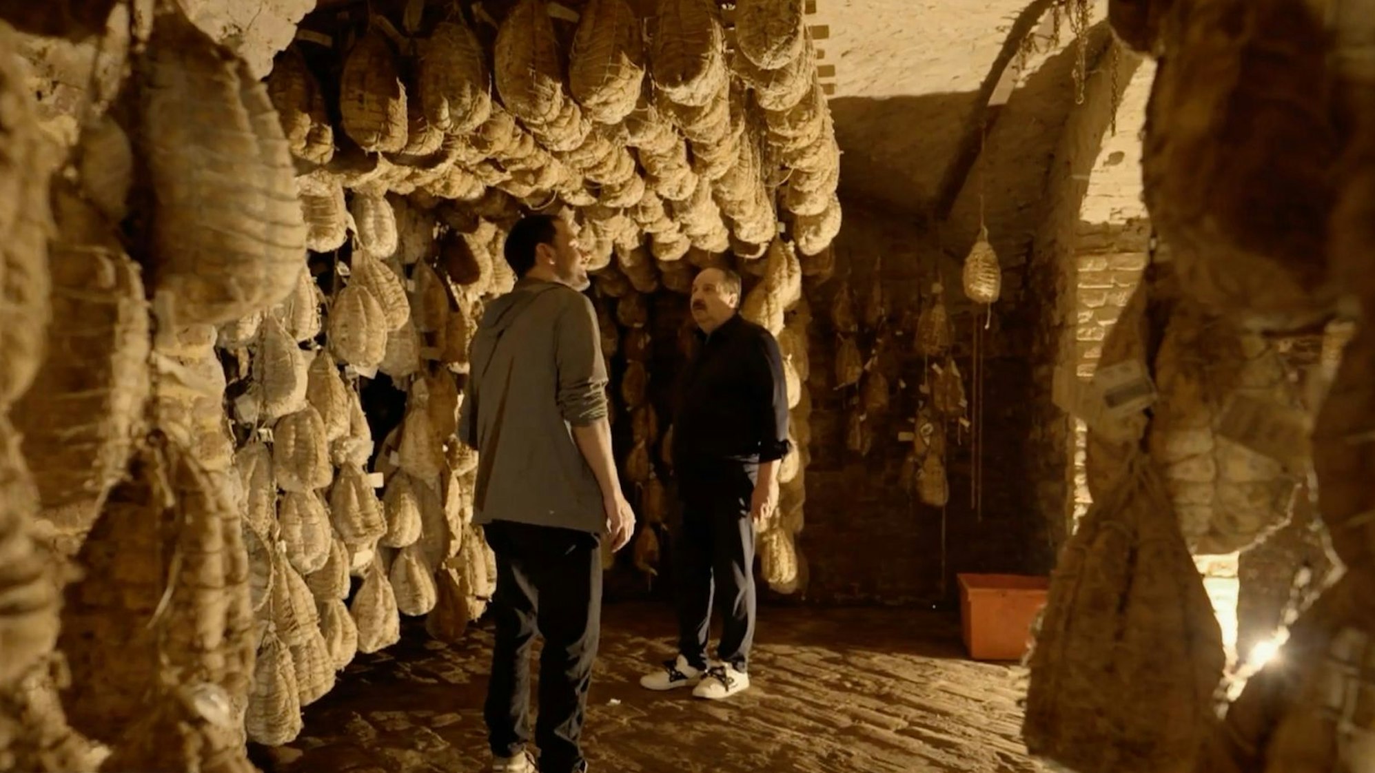 Wo gibt es die besten Zutaten? Beim Sternekoch-Kollegen Massimo Spigaroli besichtigen sie dessen „Schinkenkeller“, in dem 5.000 Culatello-Stücke lagern. (Bild: RTL)