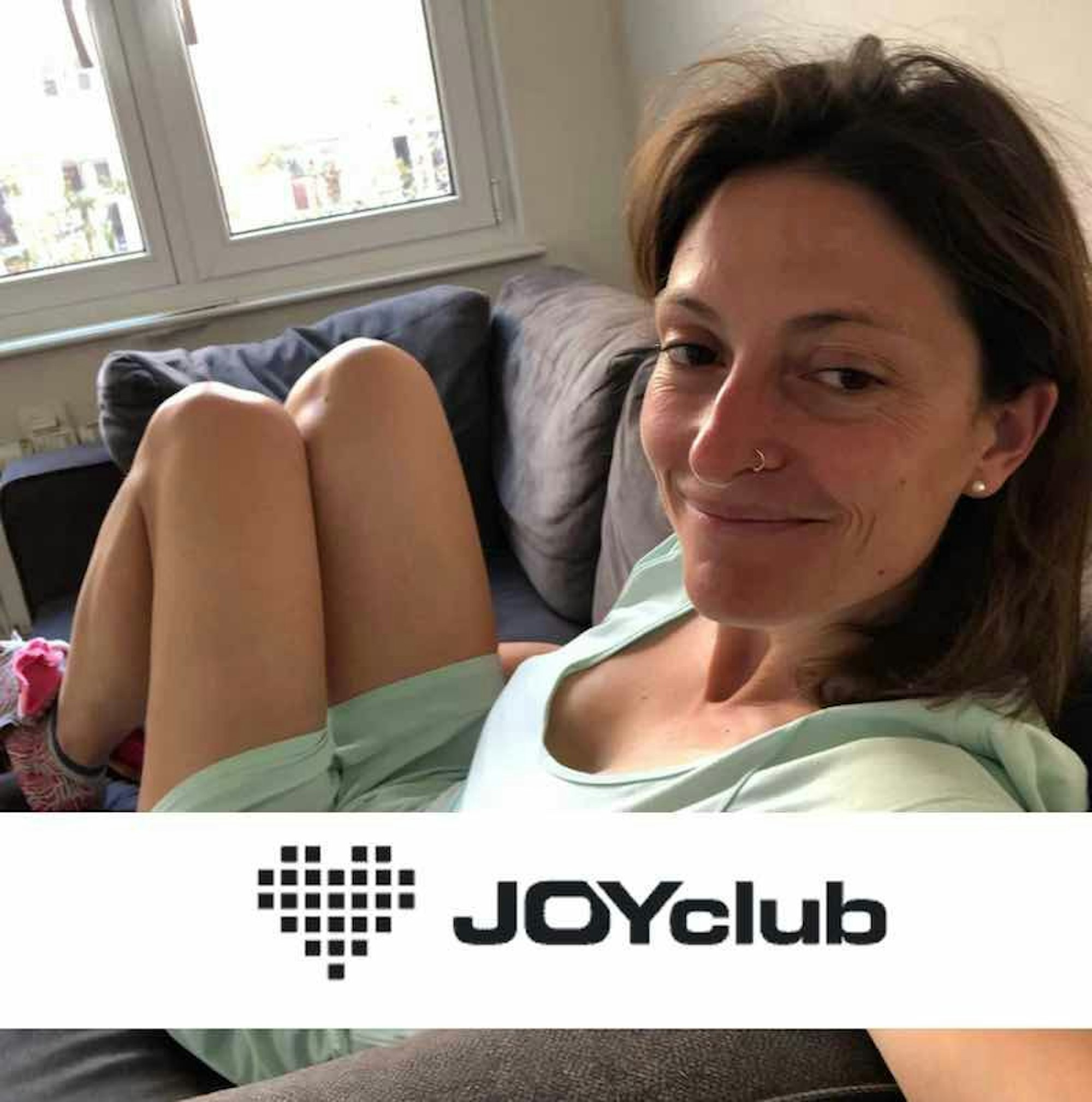 Lächelnde Frau schießt ein Foto von sich mit dem Handy.