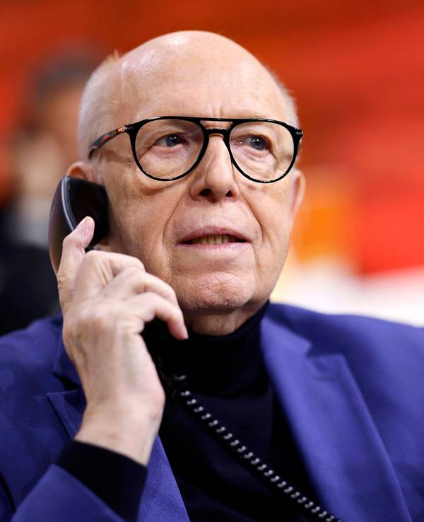 Reiner Calmund hält mit der rechten Hand ein schwarzes Telefon an sein Ohr. In der linken Hand hält er einen roten Kugelschreiber.