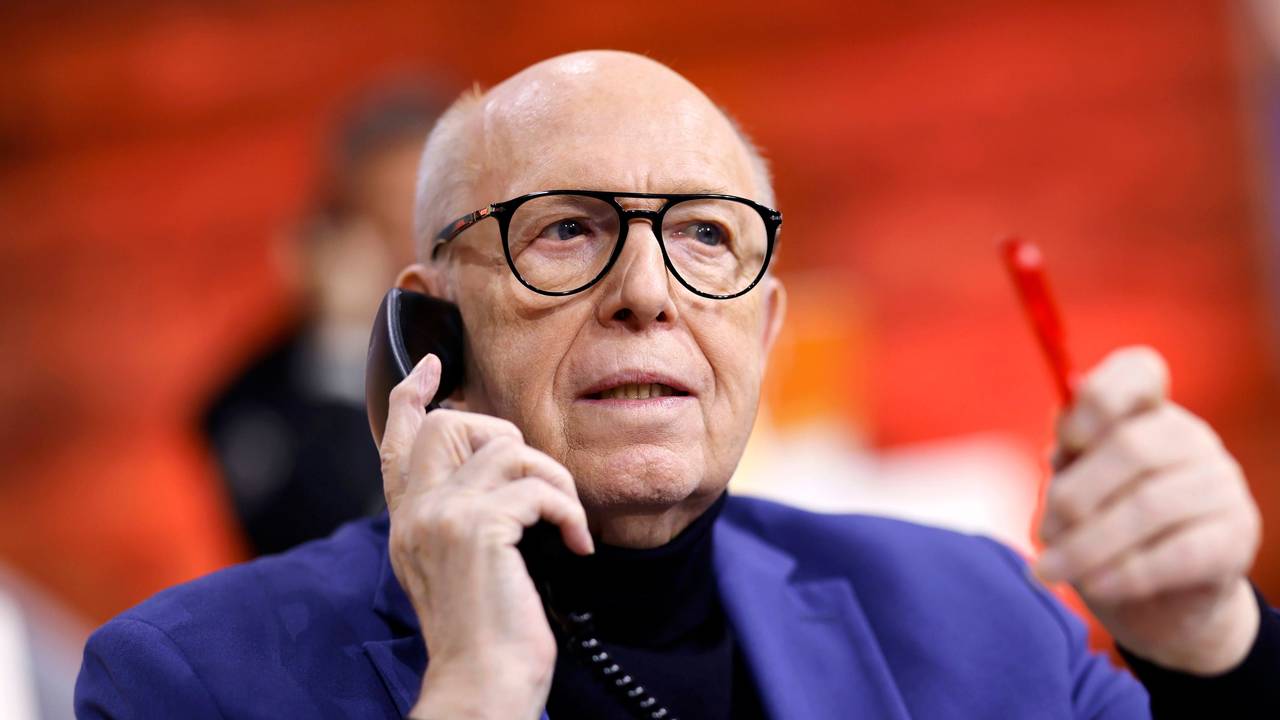 Reiner Calmund hält mit der rechten Hand ein schwarzes Telefon an sein Ohr. In der linken Hand hält er einen roten Kugelschreiber.