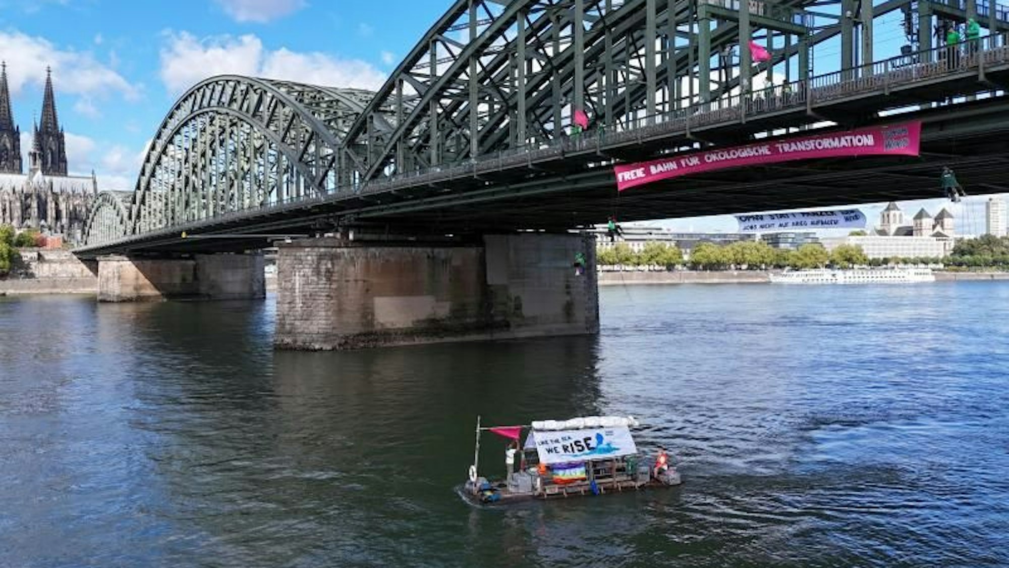 Aktivisten und Aktivistinnen von Robin Wood haben am Dienstag (2. September 2025) die Hohenzollernbrücke besetzt. Auch ein Floß ist auf dem Rhein unterwegs.